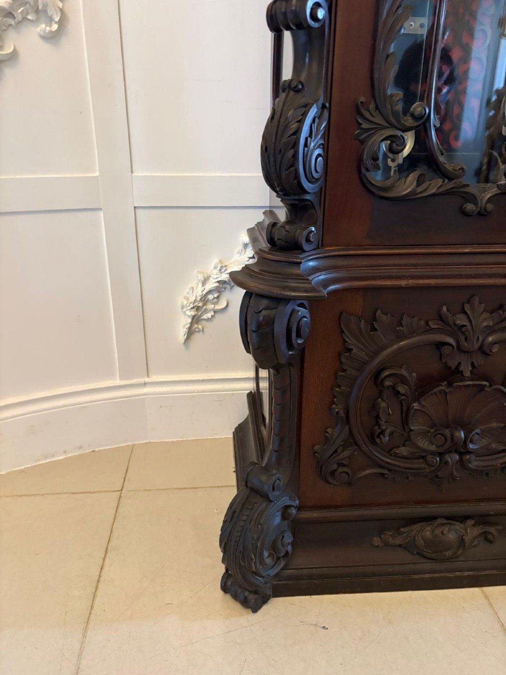 A tall carved dark mahogany longcase clock featuring an ornate pediment, brass dial with moon phase indicator, and a glazed door displaying nine tubular chimes. View XI