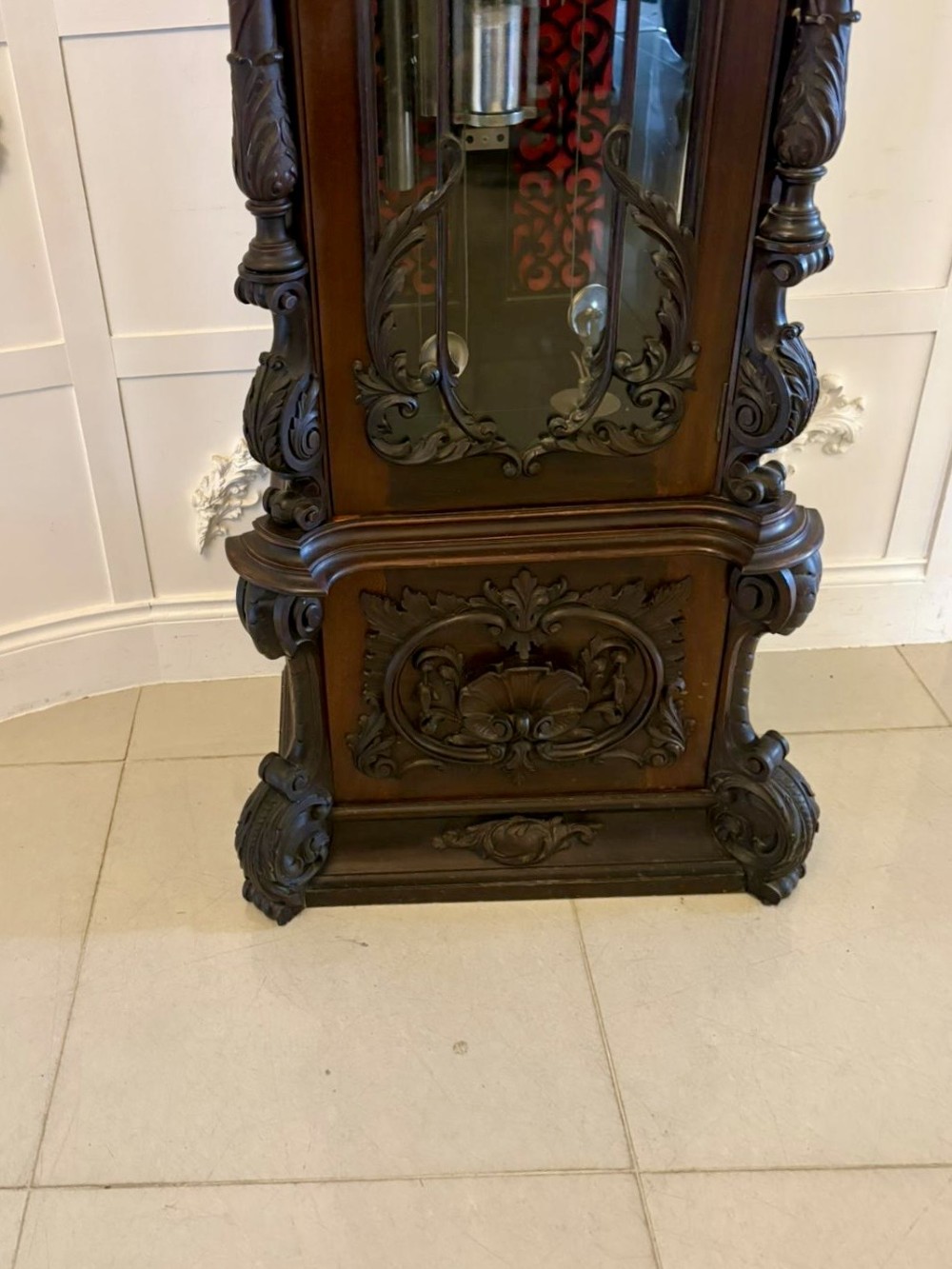 A tall carved dark mahogany longcase clock featuring an ornate pediment, brass dial with moon phase indicator, and a glazed door displaying nine tubular chimes. View XIII