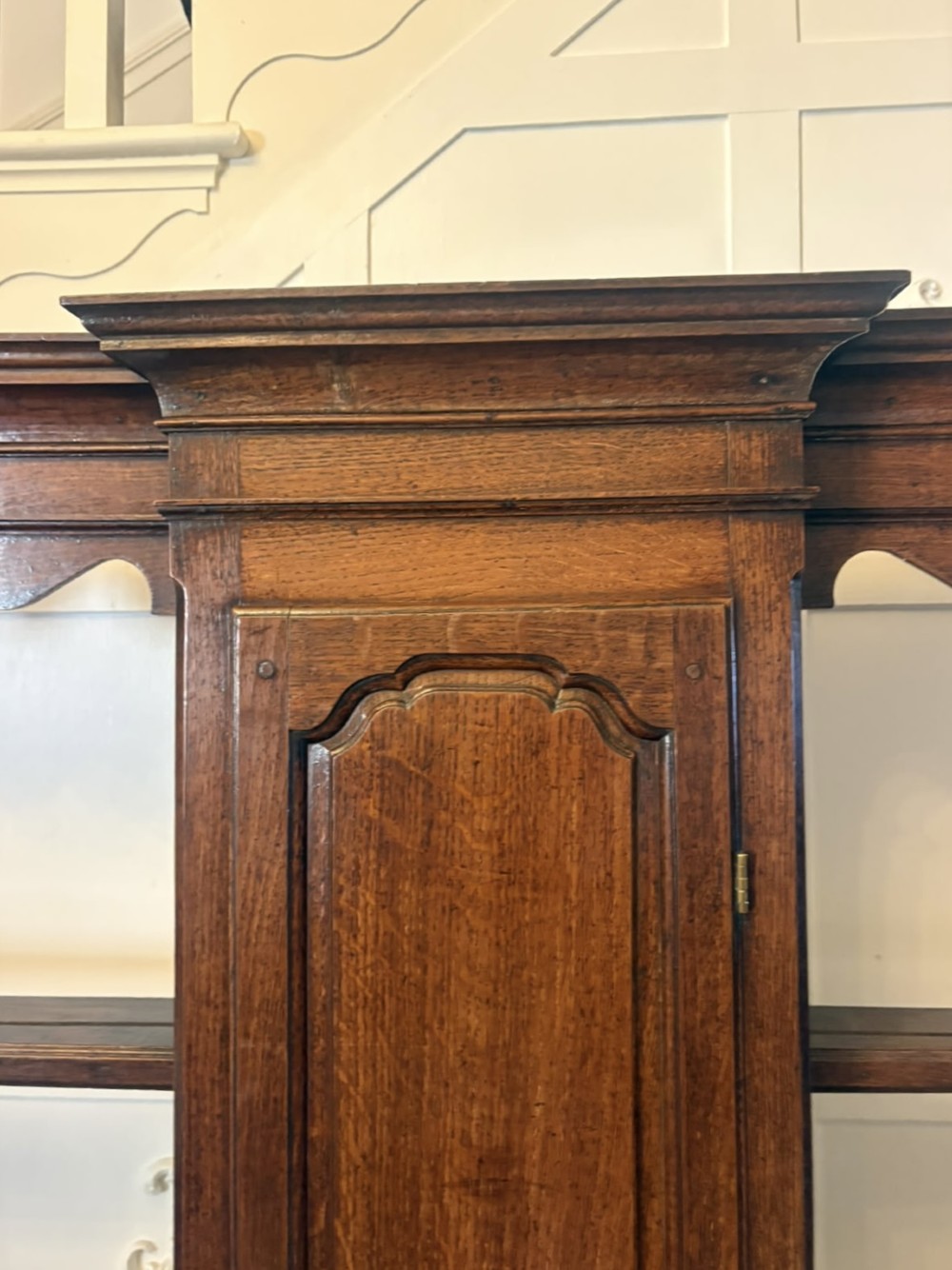 A dark oak Georgian Lancashire dresser with a scalloped open plate rack, central cupboard section, and base containing multiple drawers with brass handles. View V