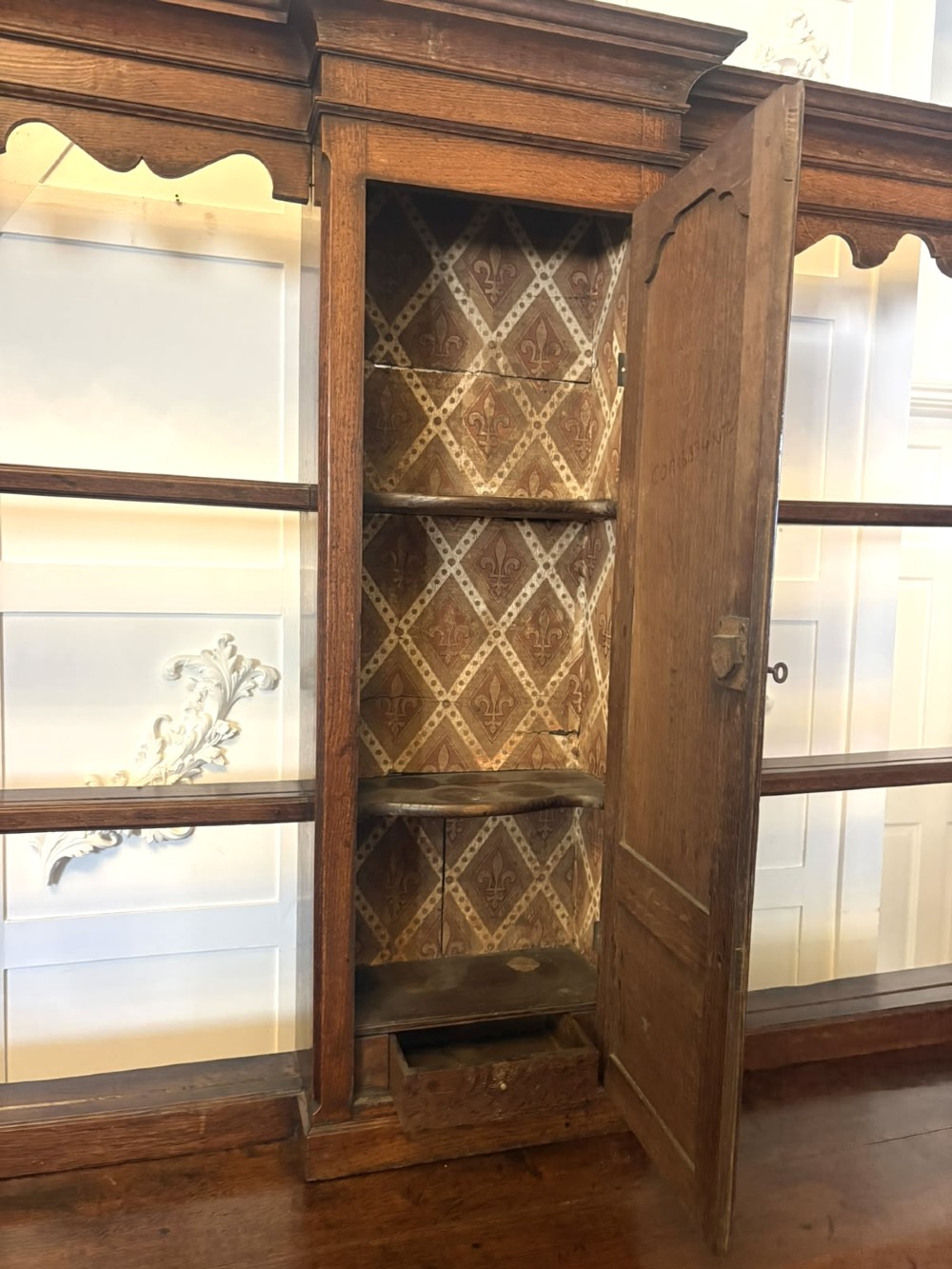 A dark oak Georgian Lancashire dresser with a scalloped open plate rack, central cupboard section, and base containing multiple drawers with brass handles. View VIII