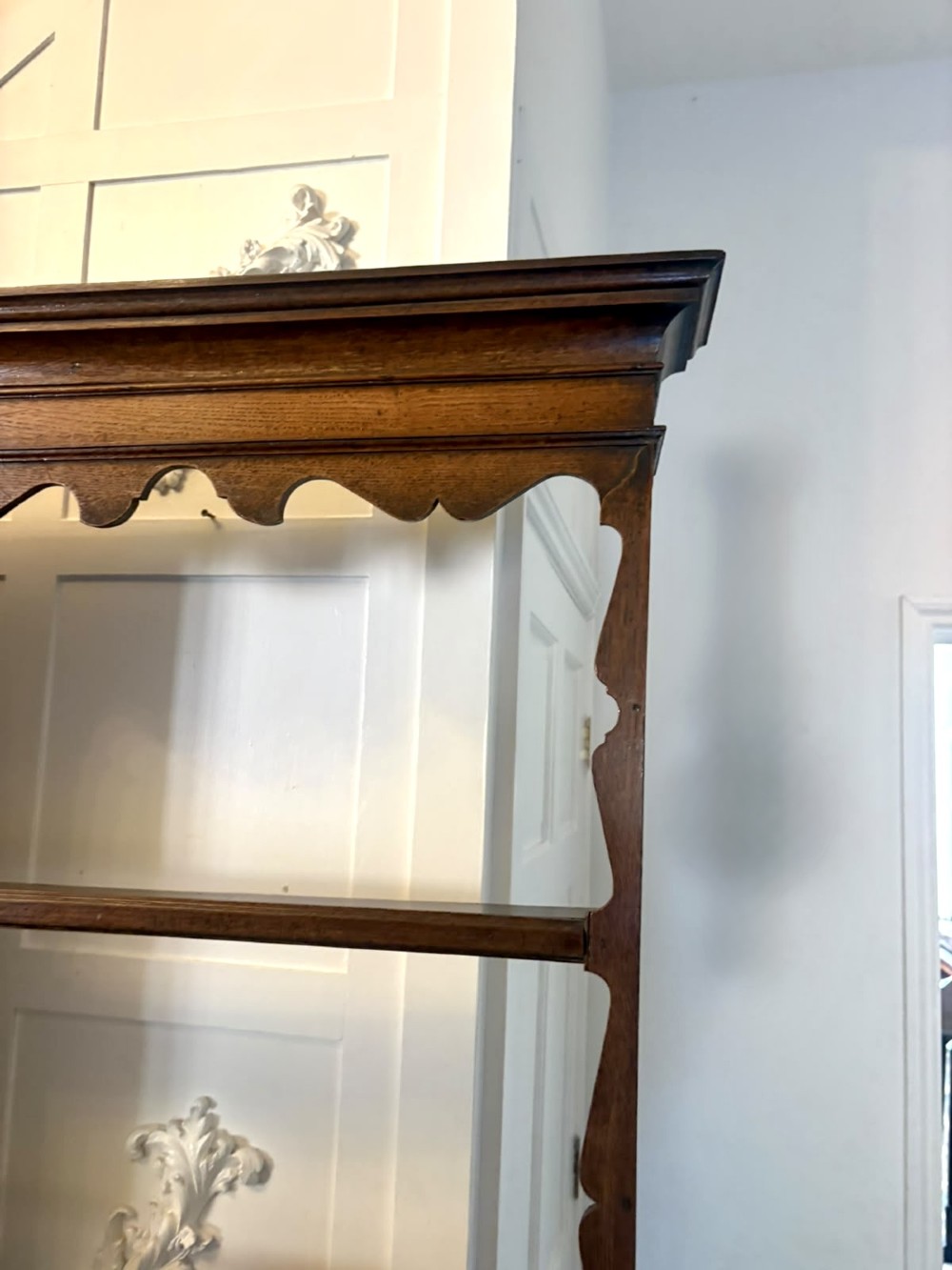 A dark oak Georgian Lancashire dresser with a scalloped open plate rack, central cupboard section, and base containing multiple drawers with brass handles. View XIII