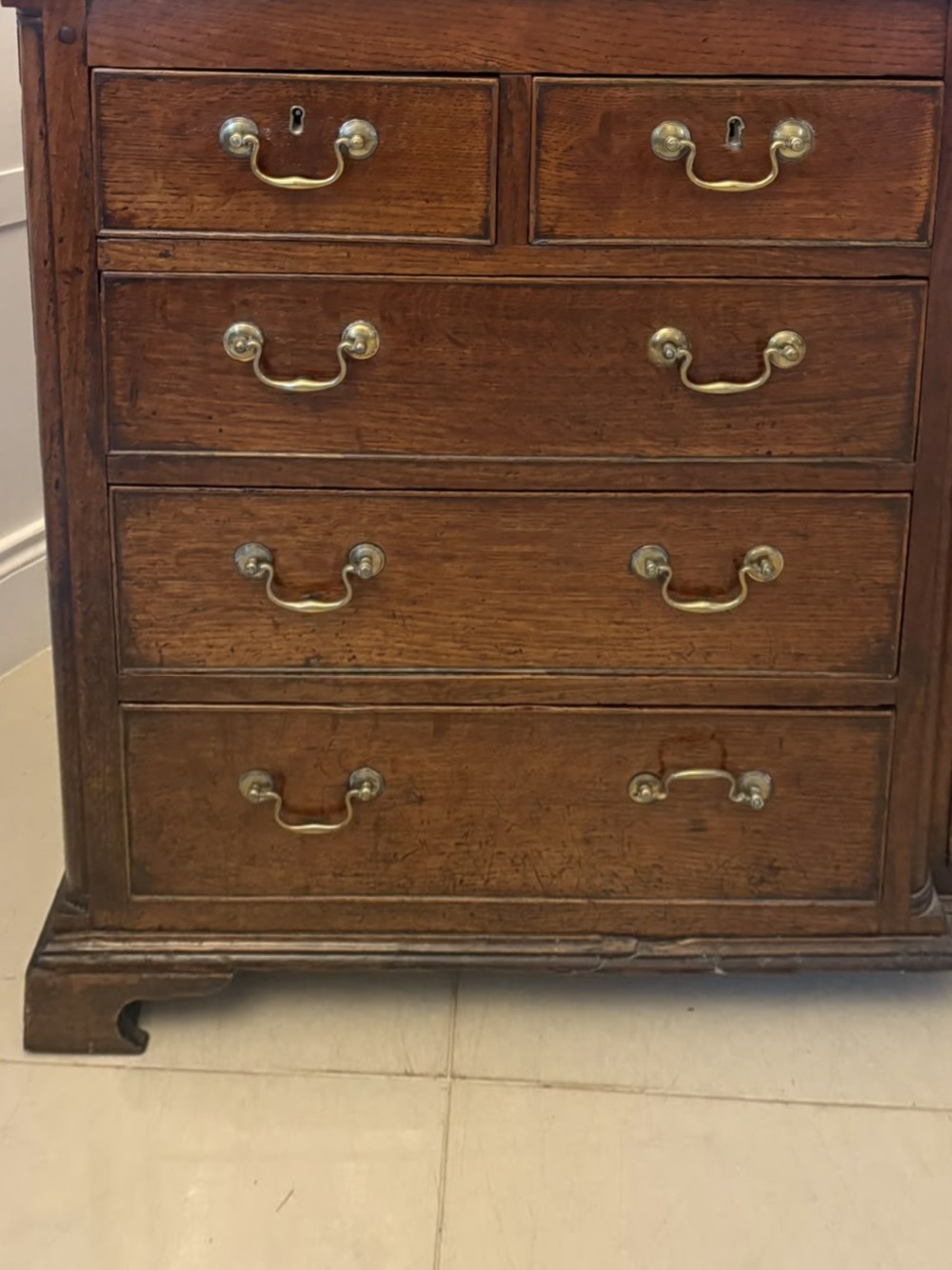 A dark oak Georgian Lancashire dresser with a scalloped open plate rack, central cupboard section, and base containing multiple drawers with brass handles. View XIV