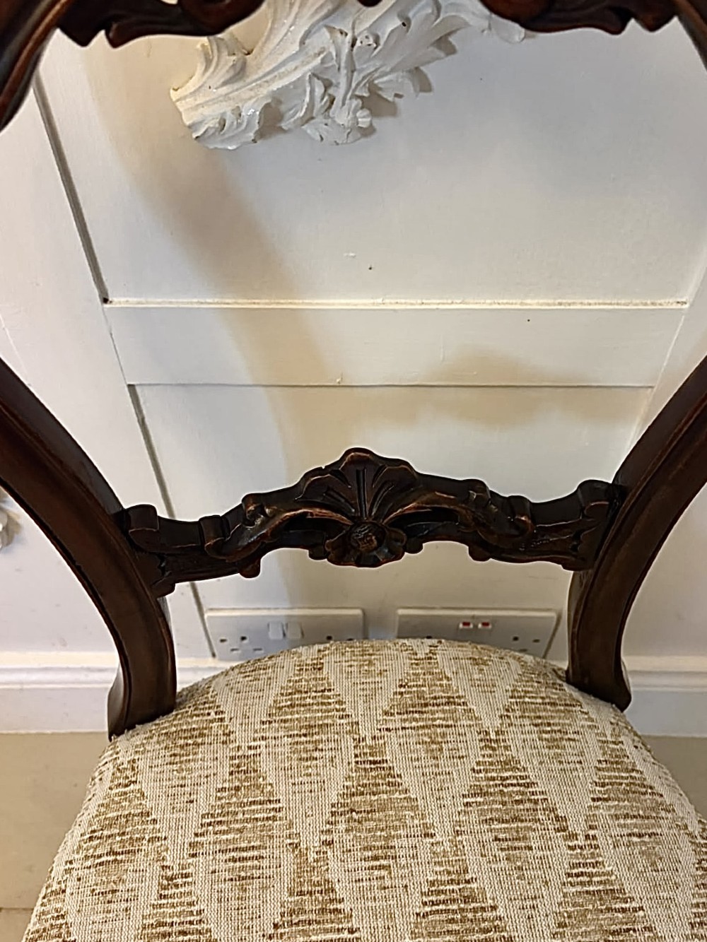 A set of four Victorian carved walnut dining chairs with open balloon-style backs and cream pattern-upholstered seats. View VI