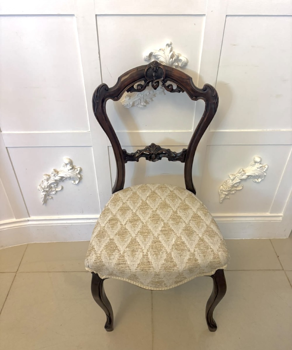 A set of four Victorian carved walnut dining chairs with open balloon-style backs and cream pattern-upholstered seats. View X