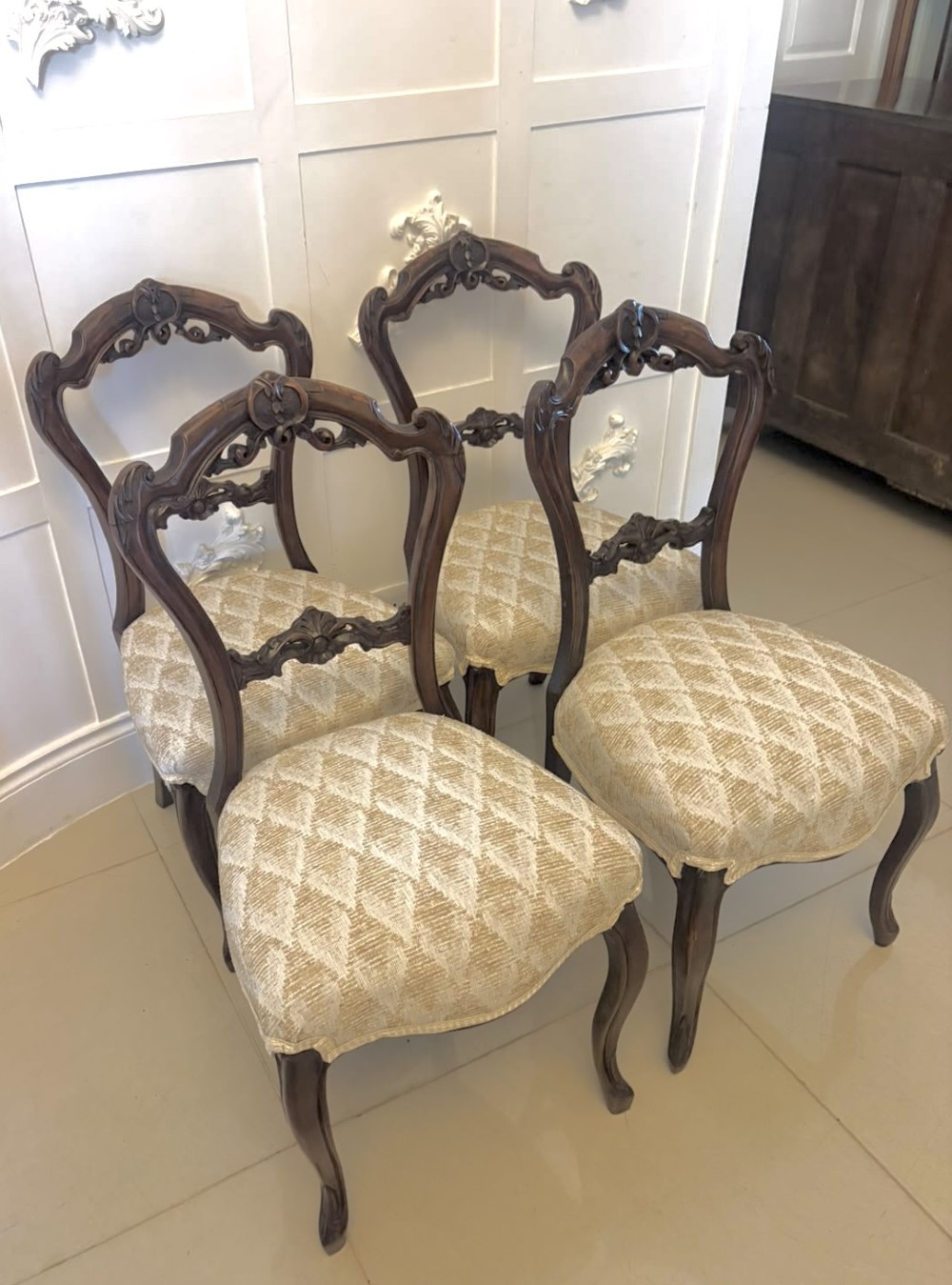 A set of four Victorian carved walnut dining chairs with open balloon-style backs and cream pattern-upholstered seats. View XV