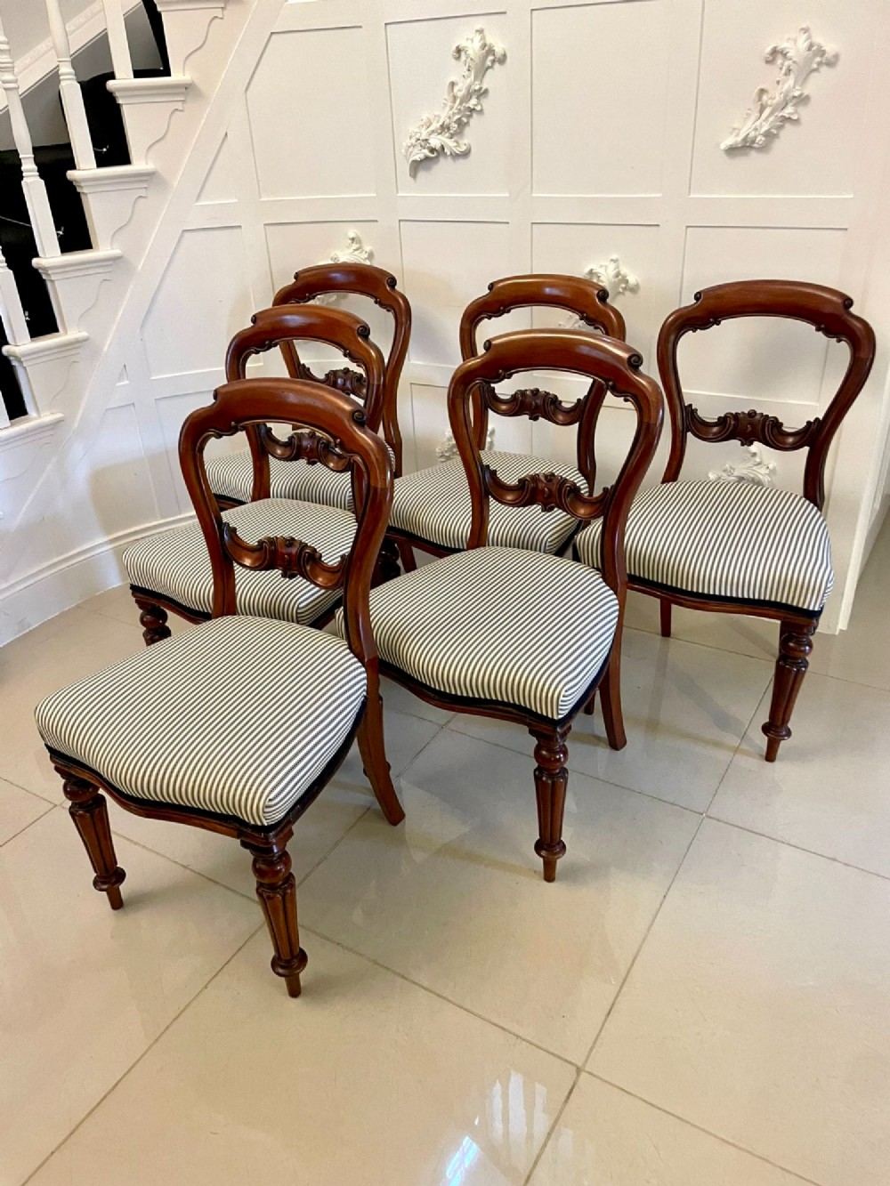 A set of six Victorian mahogany balloon back dining chairs with carved waist rails, turned front legs, and striped upholstered seats.