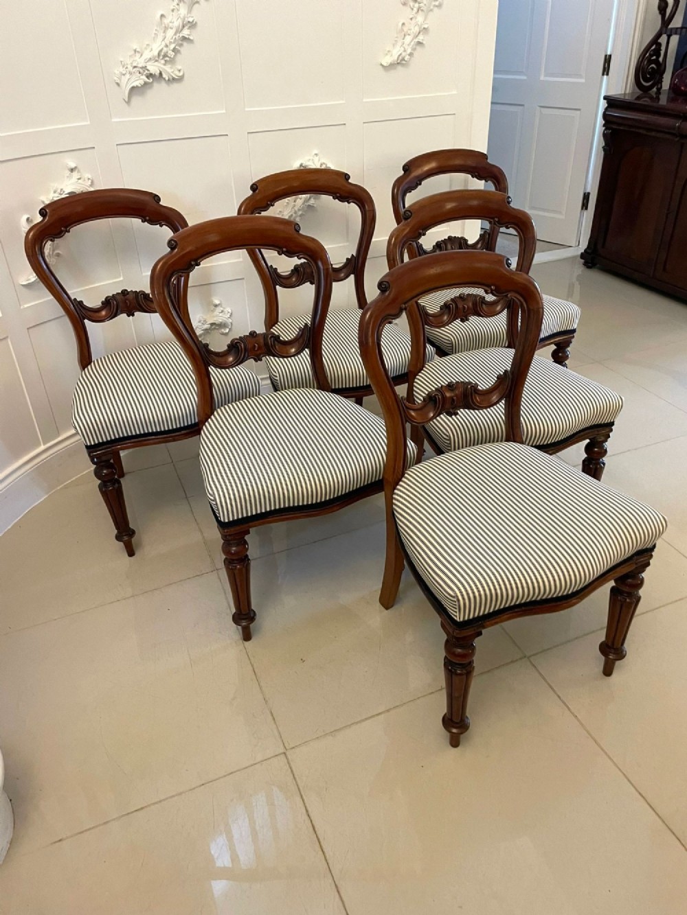 A set of six Victorian mahogany balloon back dining chairs with carved waist rails, turned front legs, and striped upholstered seats. View X
