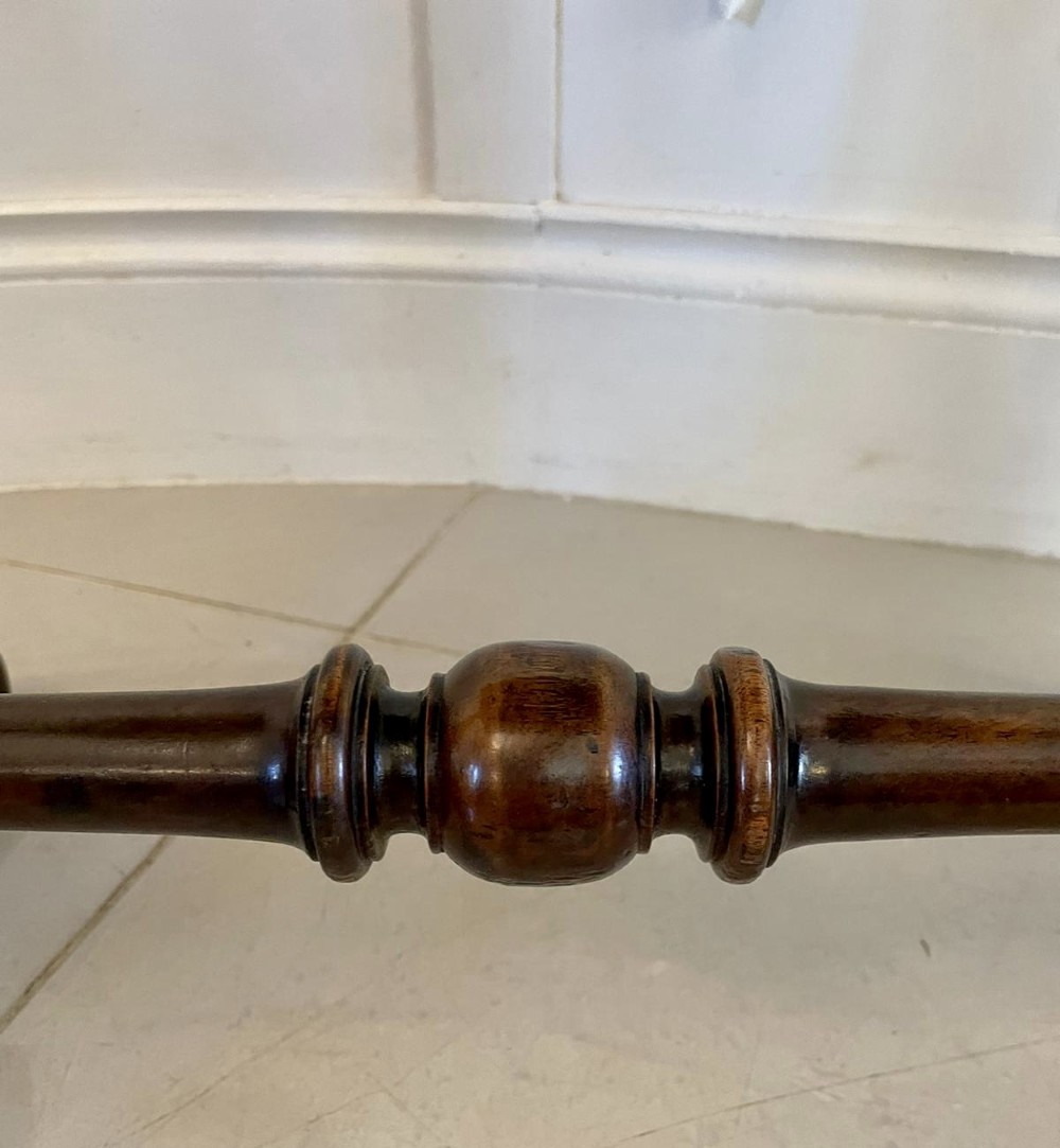 An antique Victorian circular mahogany lamp table featuring a central turned stem with an integrated balustrade mid-tier gallery, resting on a tripod base with scroll feet. View II