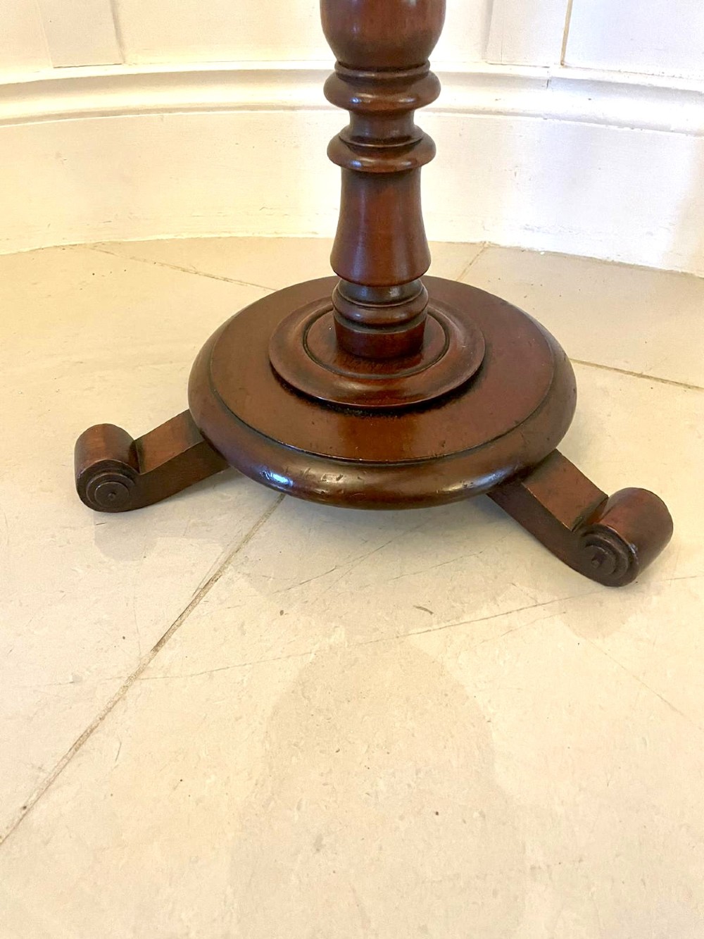 An antique Victorian circular mahogany lamp table featuring a central turned stem with an integrated balustrade mid-tier gallery, resting on a tripod base with scroll feet. View IV