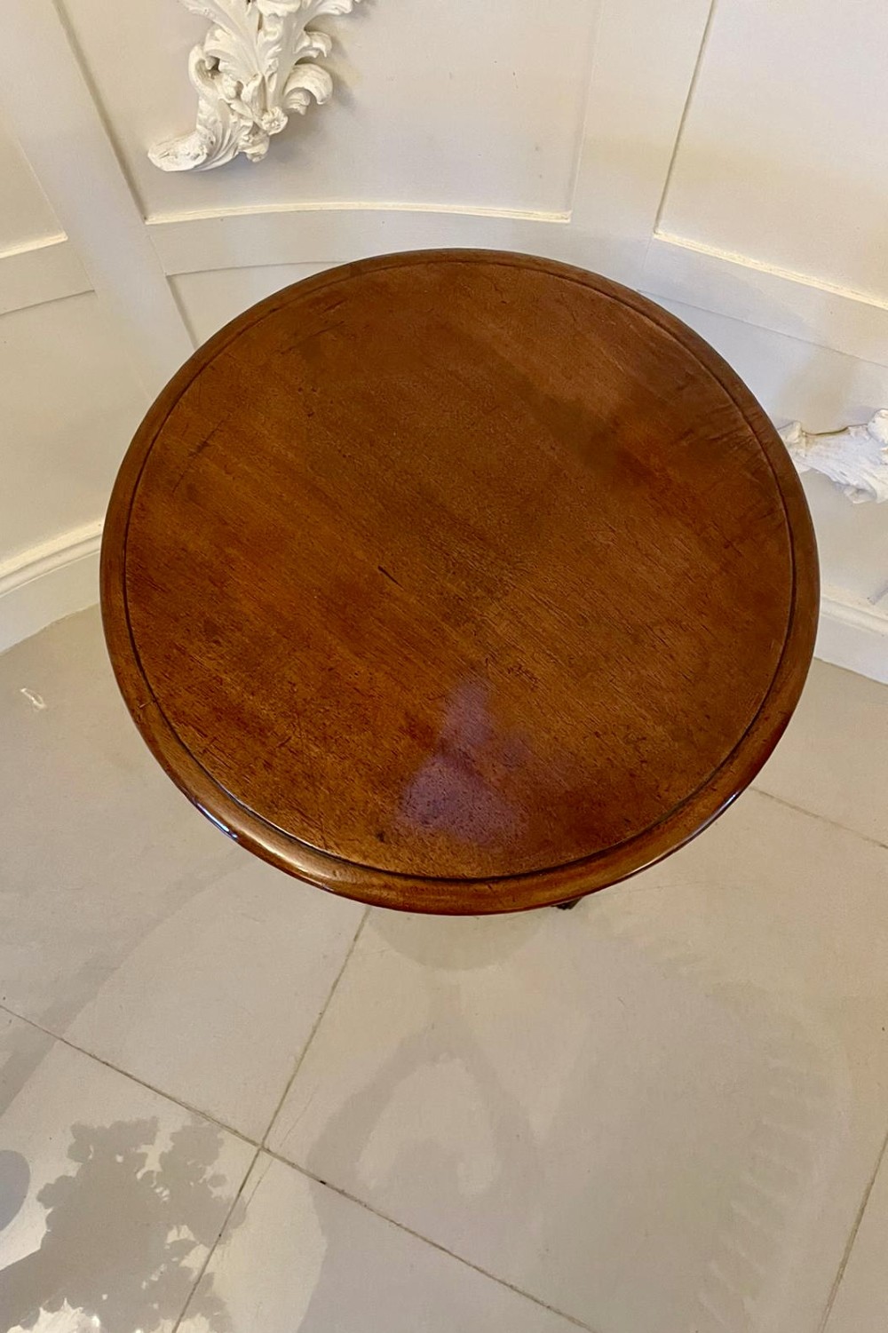 An antique Victorian circular mahogany lamp table featuring a central turned stem with an integrated balustrade mid-tier gallery, resting on a tripod base with scroll feet. View VI