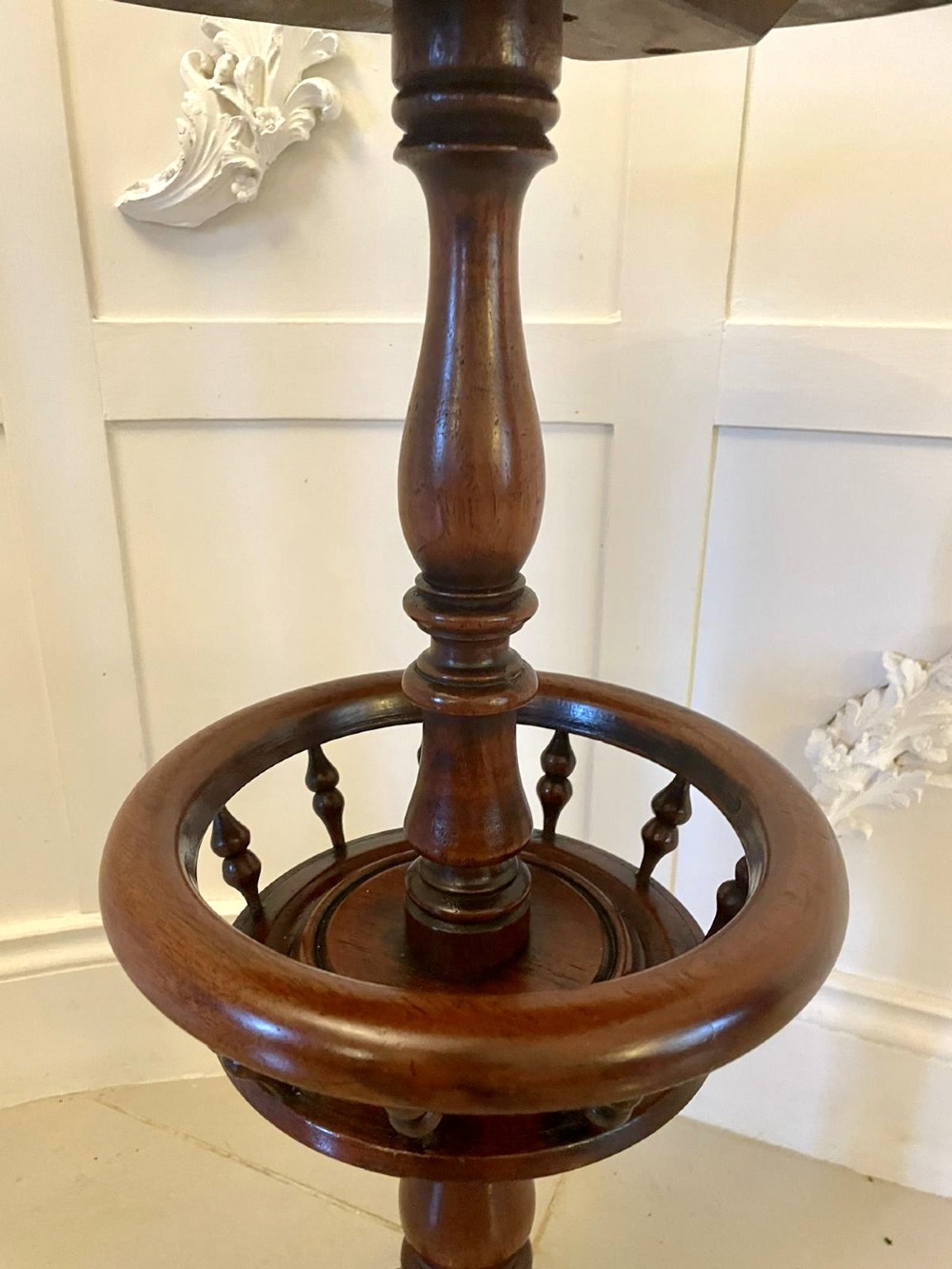 An antique Victorian circular mahogany lamp table featuring a central turned stem with an integrated balustrade mid-tier gallery, resting on a tripod base with scroll feet. View VII