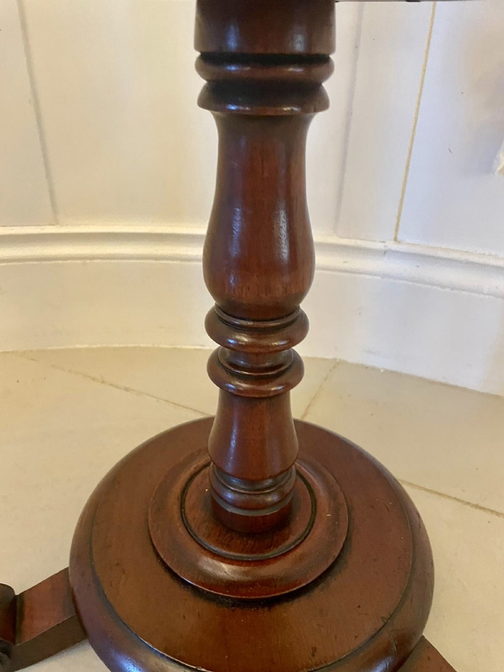 An antique Victorian circular mahogany lamp table featuring a central turned stem with an integrated balustrade mid-tier gallery, resting on a tripod base with scroll feet. View XI
