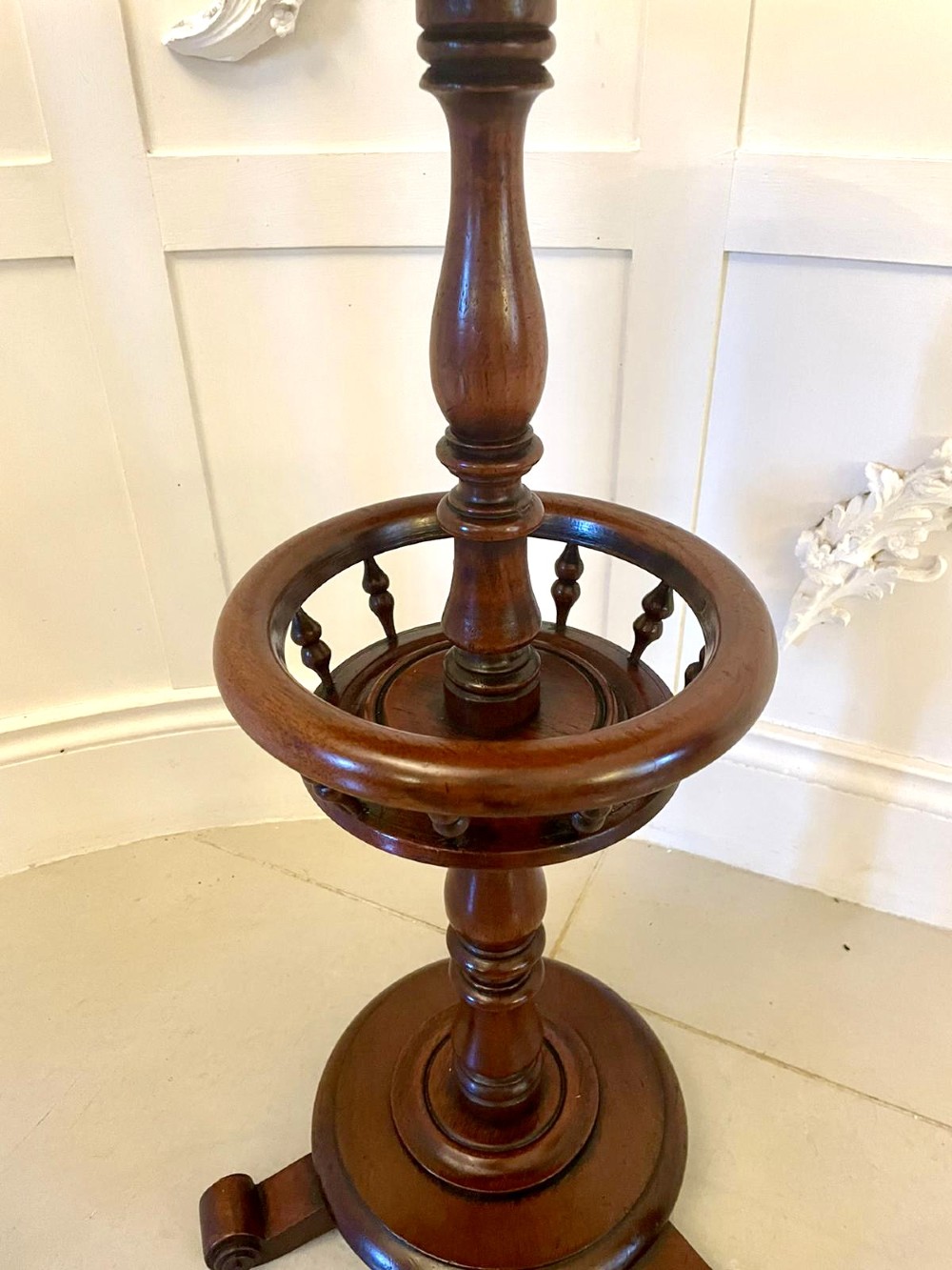 An antique Victorian circular mahogany lamp table featuring a central turned stem with an integrated balustrade mid-tier gallery, resting on a tripod base with scroll feet. View XII