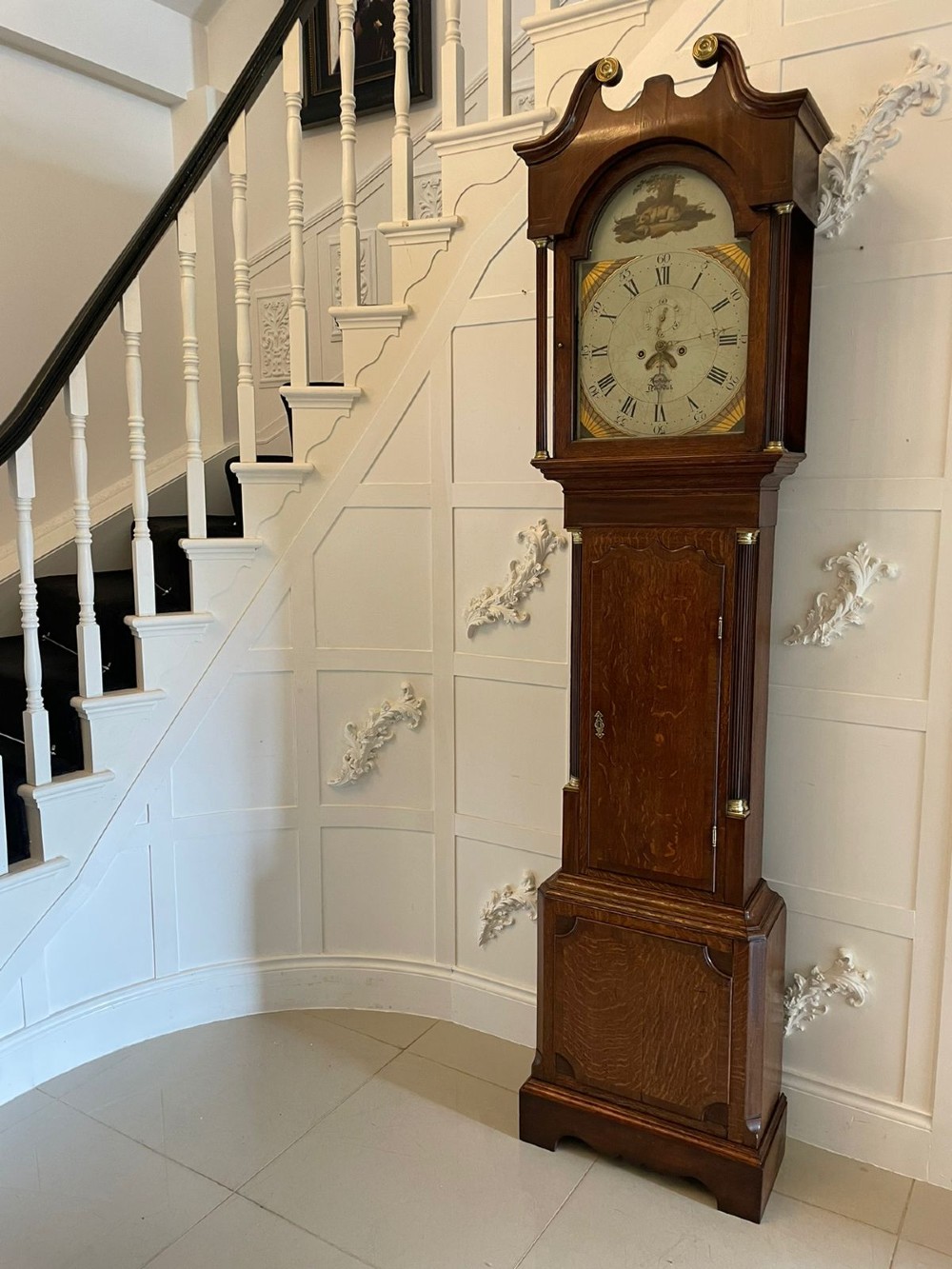 An antique George III oak longcase clock featuring a swan-neck pediment, brass fittings, and a painted arch dial with Roman numerals. View II