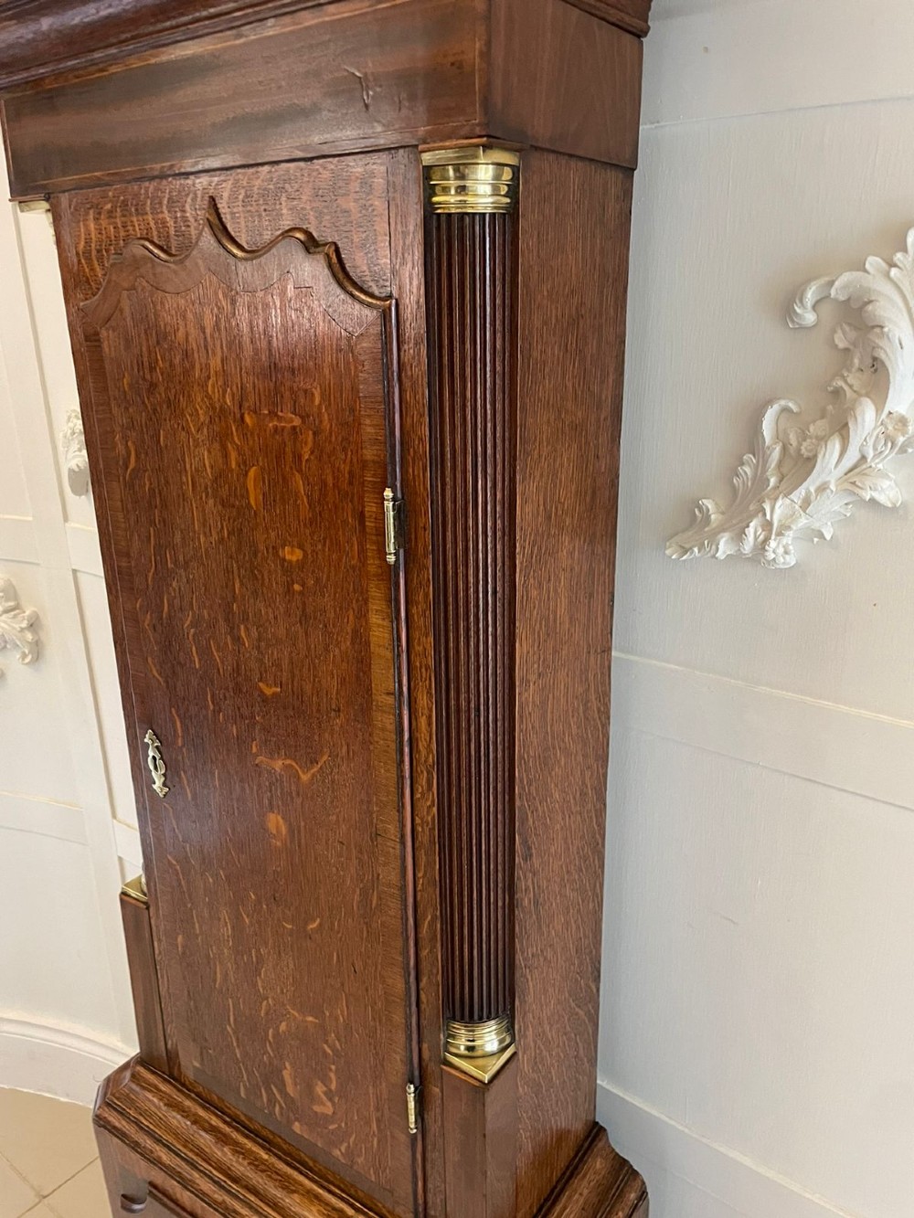 An antique George III oak longcase clock featuring a swan-neck pediment, brass fittings, and a painted arch dial with Roman numerals. View III