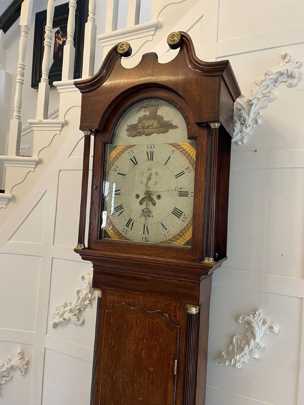 An antique George III oak longcase clock featuring a swan-neck pediment, brass fittings, and a painted arch dial with Roman numerals. View VI