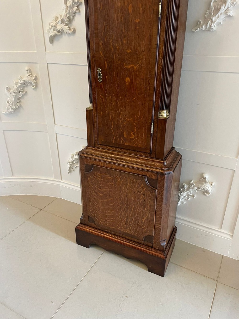 An antique George III oak longcase clock featuring a swan-neck pediment, brass fittings, and a painted arch dial with Roman numerals. View VII