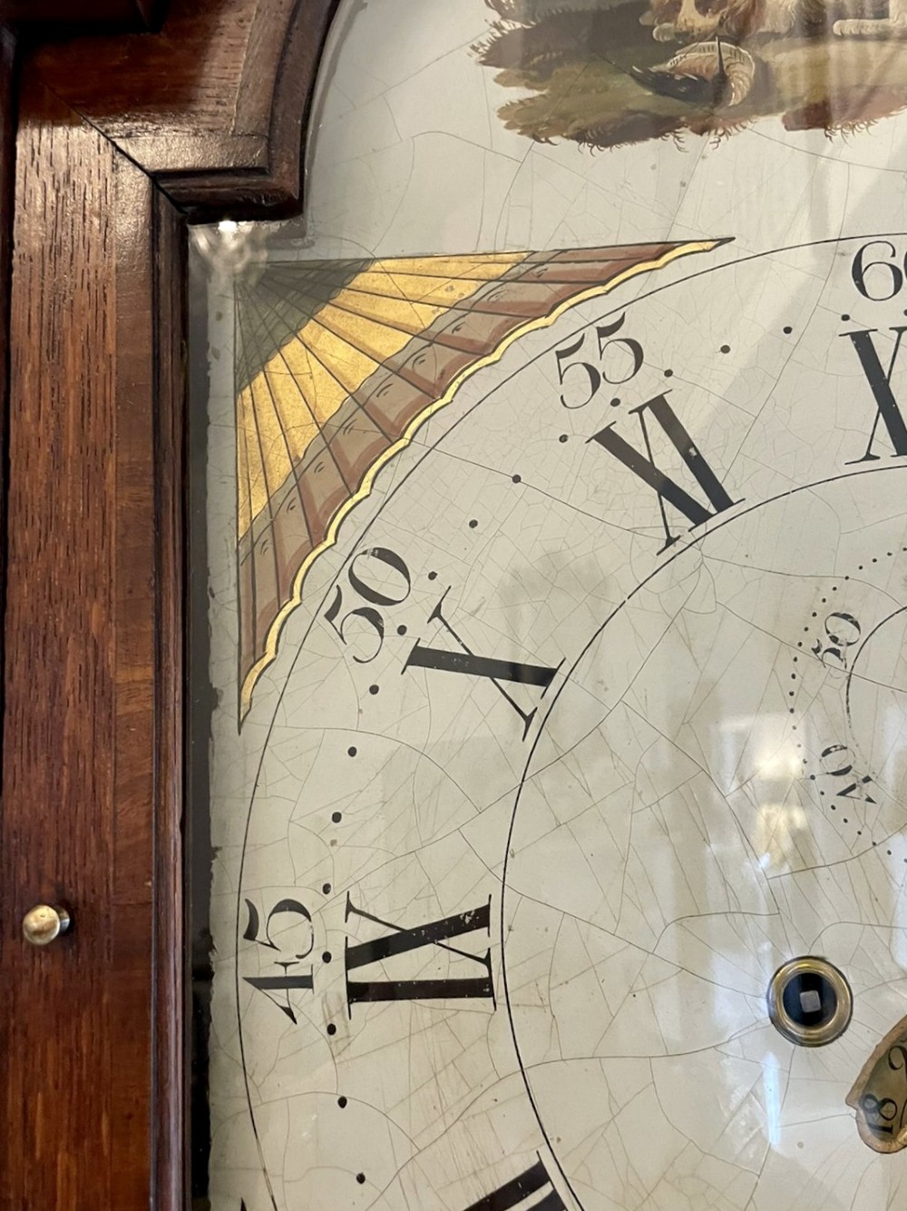 An antique George III oak longcase clock featuring a swan-neck pediment, brass fittings, and a painted arch dial with Roman numerals. View X