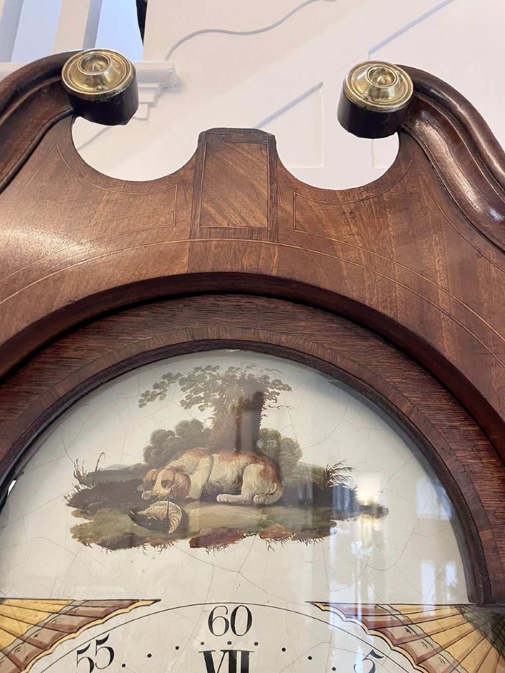 An antique George III oak longcase clock featuring a swan-neck pediment, brass fittings, and a painted arch dial with Roman numerals. View XI