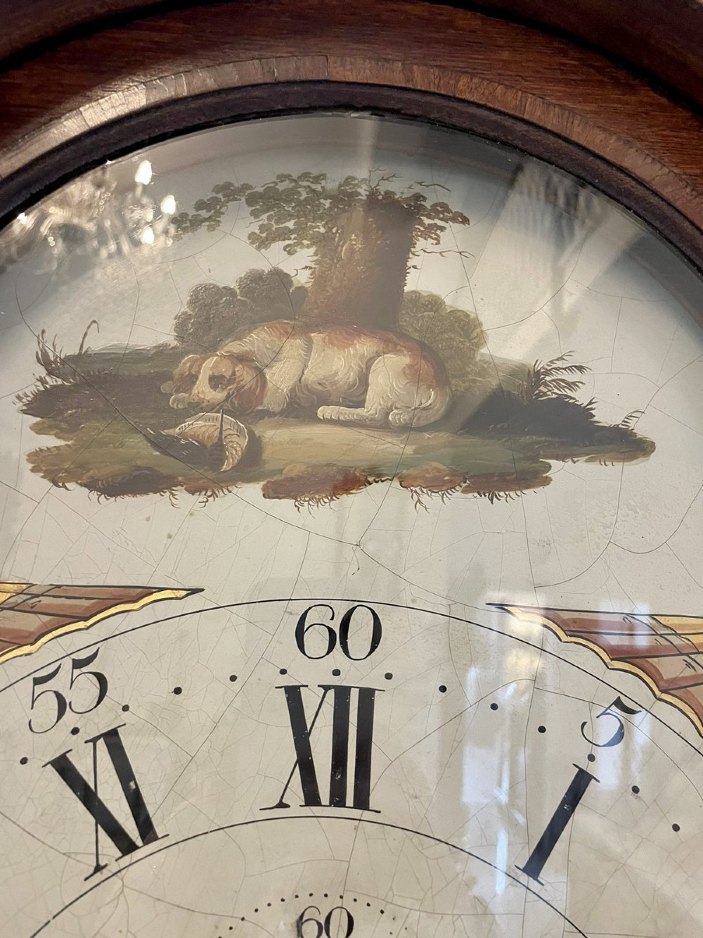An antique George III oak longcase clock featuring a swan-neck pediment, brass fittings, and a painted arch dial with Roman numerals. View XII