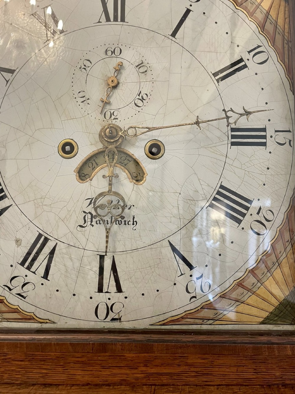 An antique George III oak longcase clock featuring a swan-neck pediment, brass fittings, and a painted arch dial with Roman numerals. View XIII