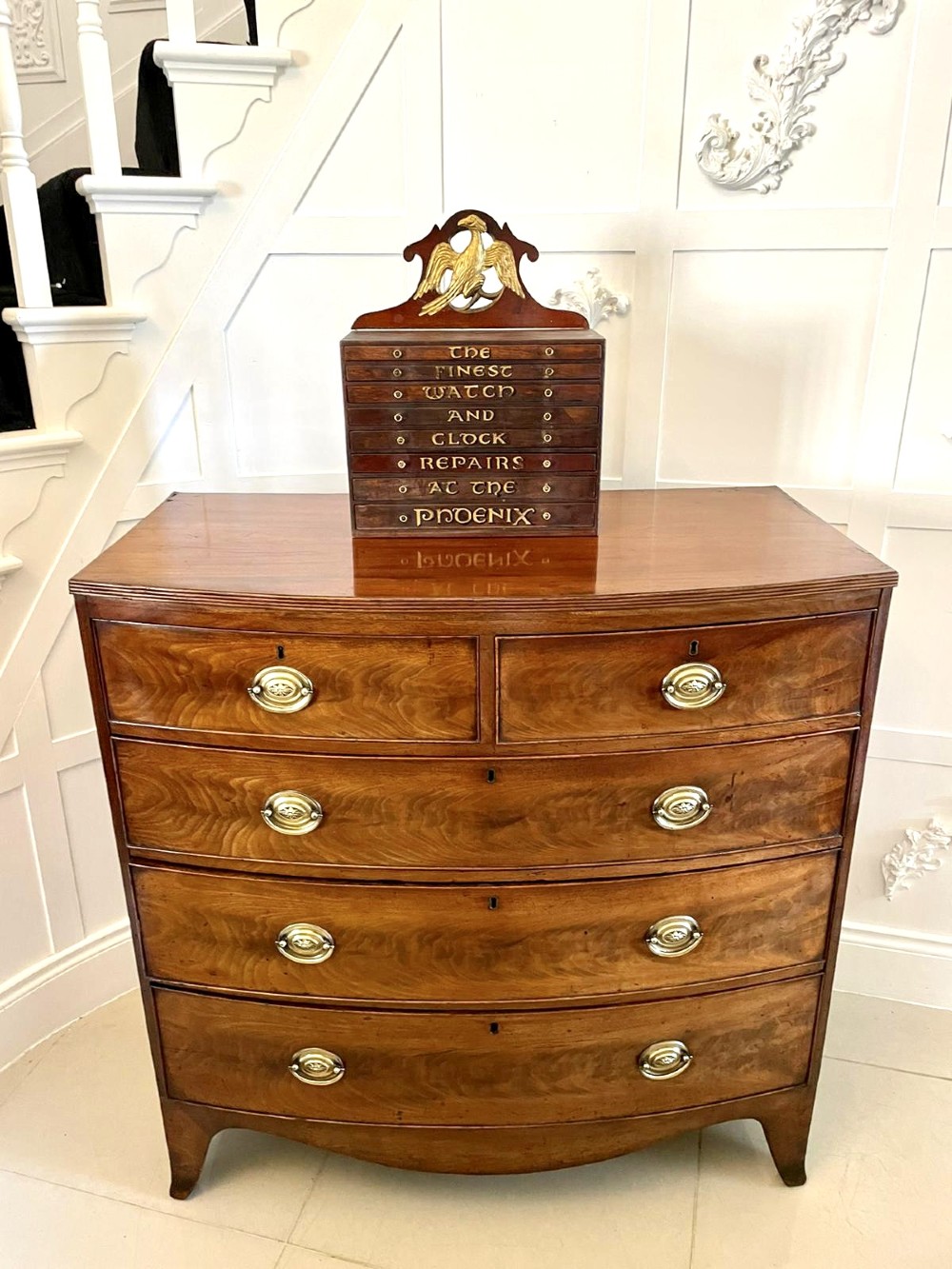 A dark wood Victorian desktop chest of eight shallow drawers featuring carved gilt lettering and a carved phoenix crest on the pediment. View II