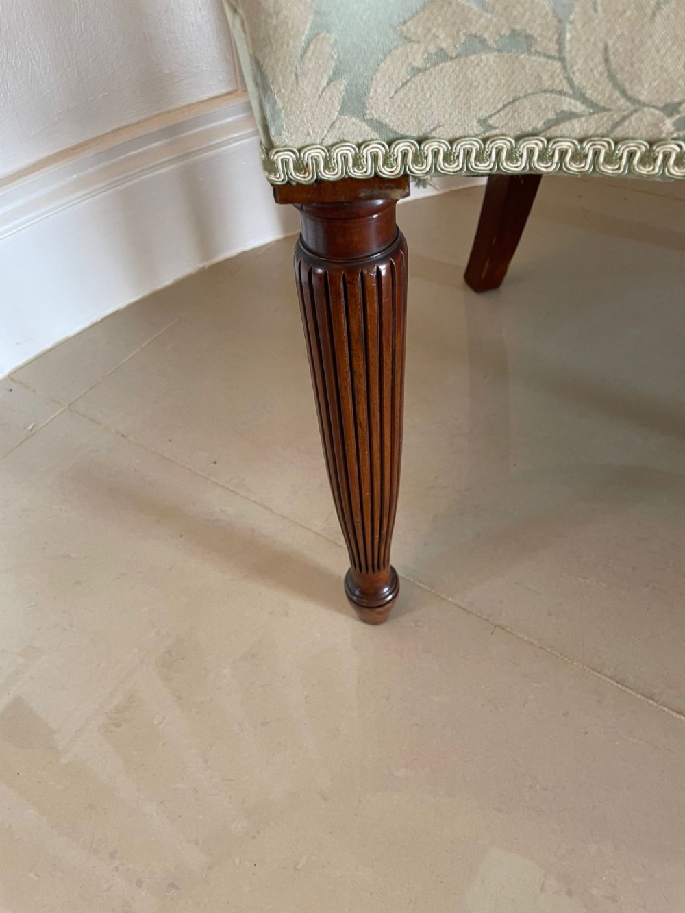 A pair of carved mahogany open armchairs featuring oval backs with carved splats, padded armrests, and pale green patterned fabric seats on fluted front legs. View V