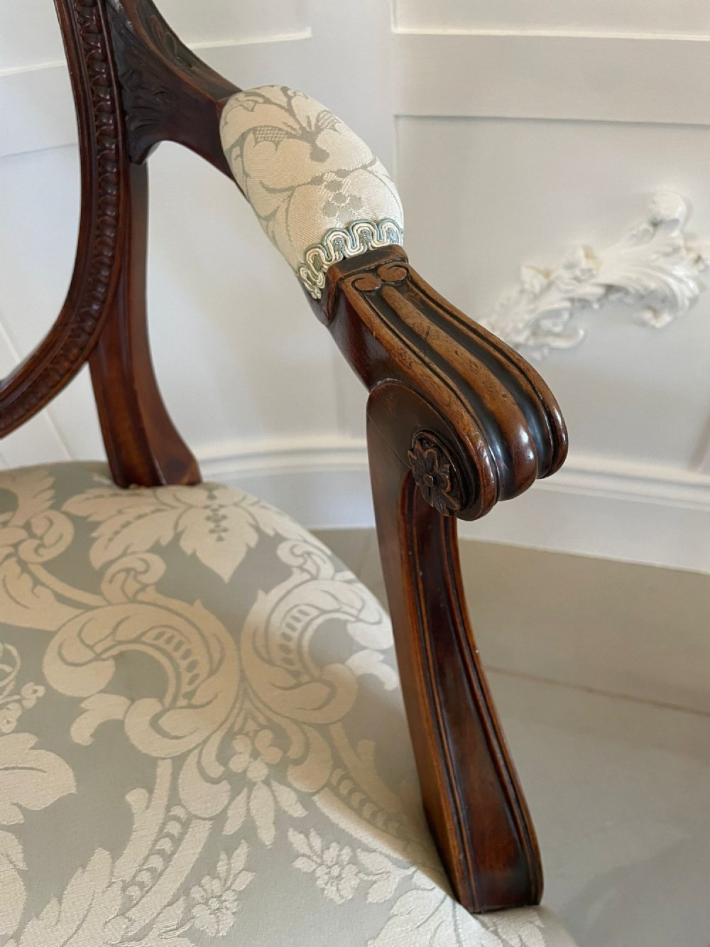 A pair of carved mahogany open armchairs featuring oval backs with carved splats, padded armrests, and pale green patterned fabric seats on fluted front legs. View VI