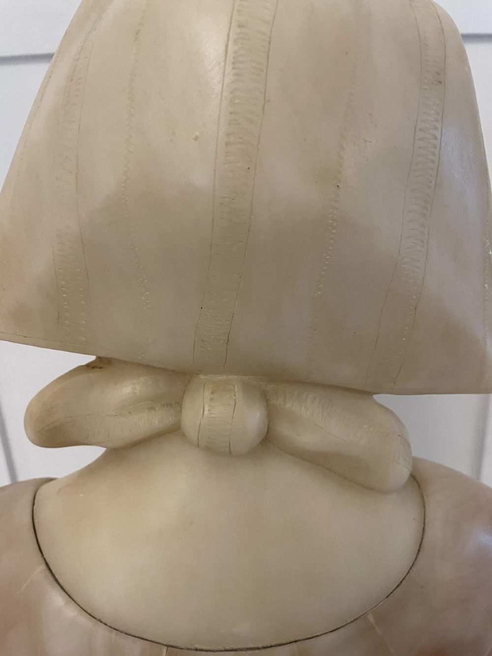 Carved Victorian alabaster bust depicting a young woman wearing a traditional bonnet, mounted on an octagonal marble base. View V