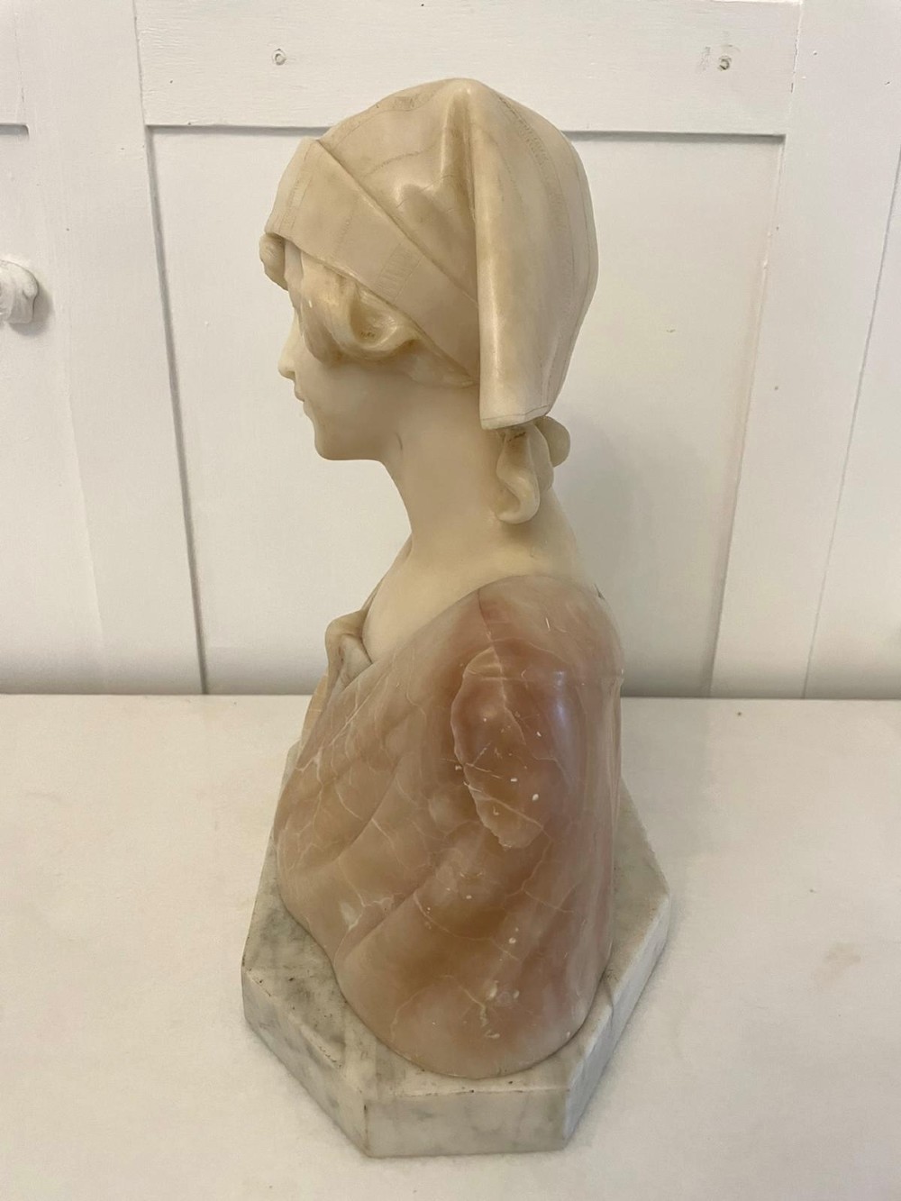 Carved Victorian alabaster bust depicting a young woman wearing a traditional bonnet, mounted on an octagonal marble base. View VIII