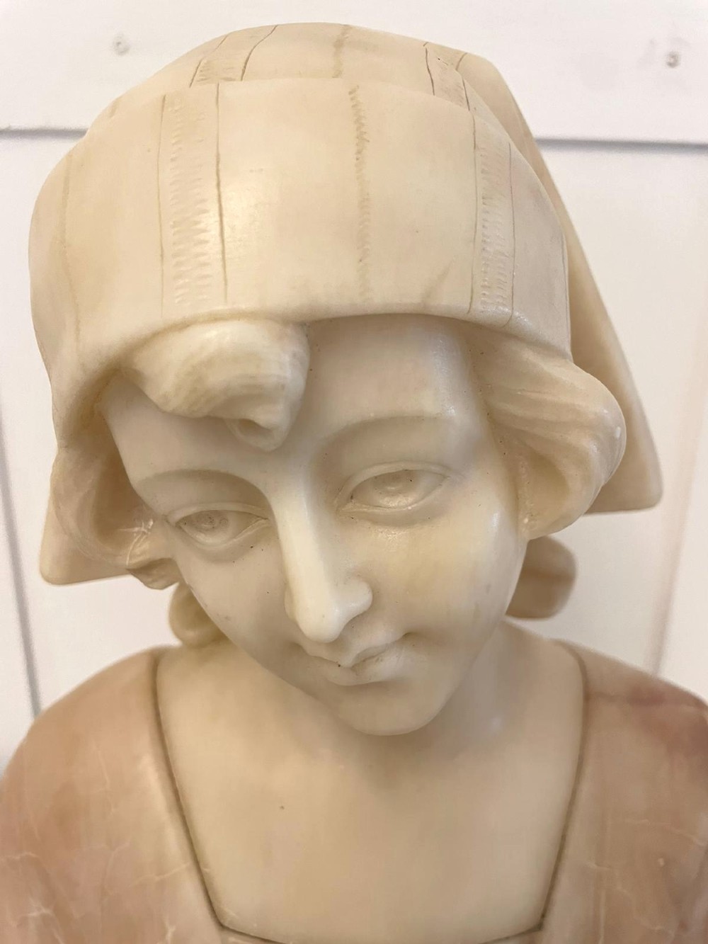 Carved Victorian alabaster bust depicting a young woman wearing a traditional bonnet, mounted on an octagonal marble base. View XI
