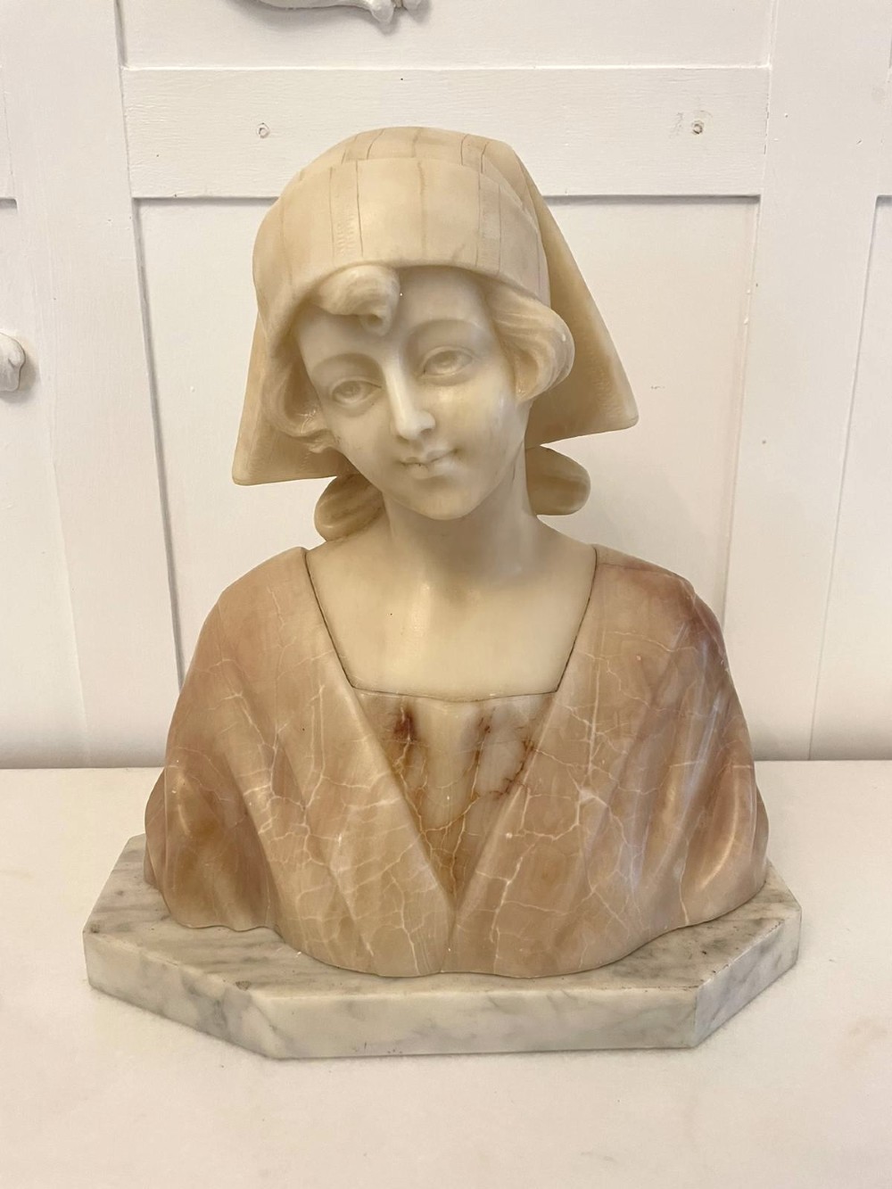 Carved Victorian alabaster bust depicting a young woman wearing a traditional bonnet, mounted on an octagonal marble base. View XIV