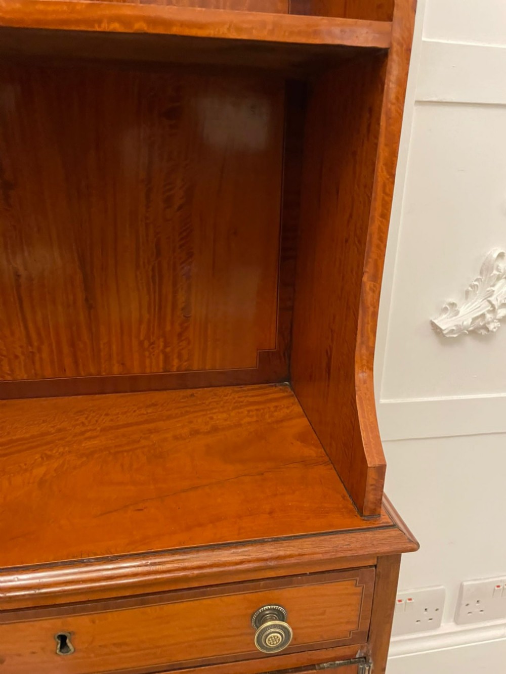 A pair of tall satinwood waterfall bookcases featuring tiered open shelves with brass gallery rails, single drawers, and lower panelled cupboards. View III