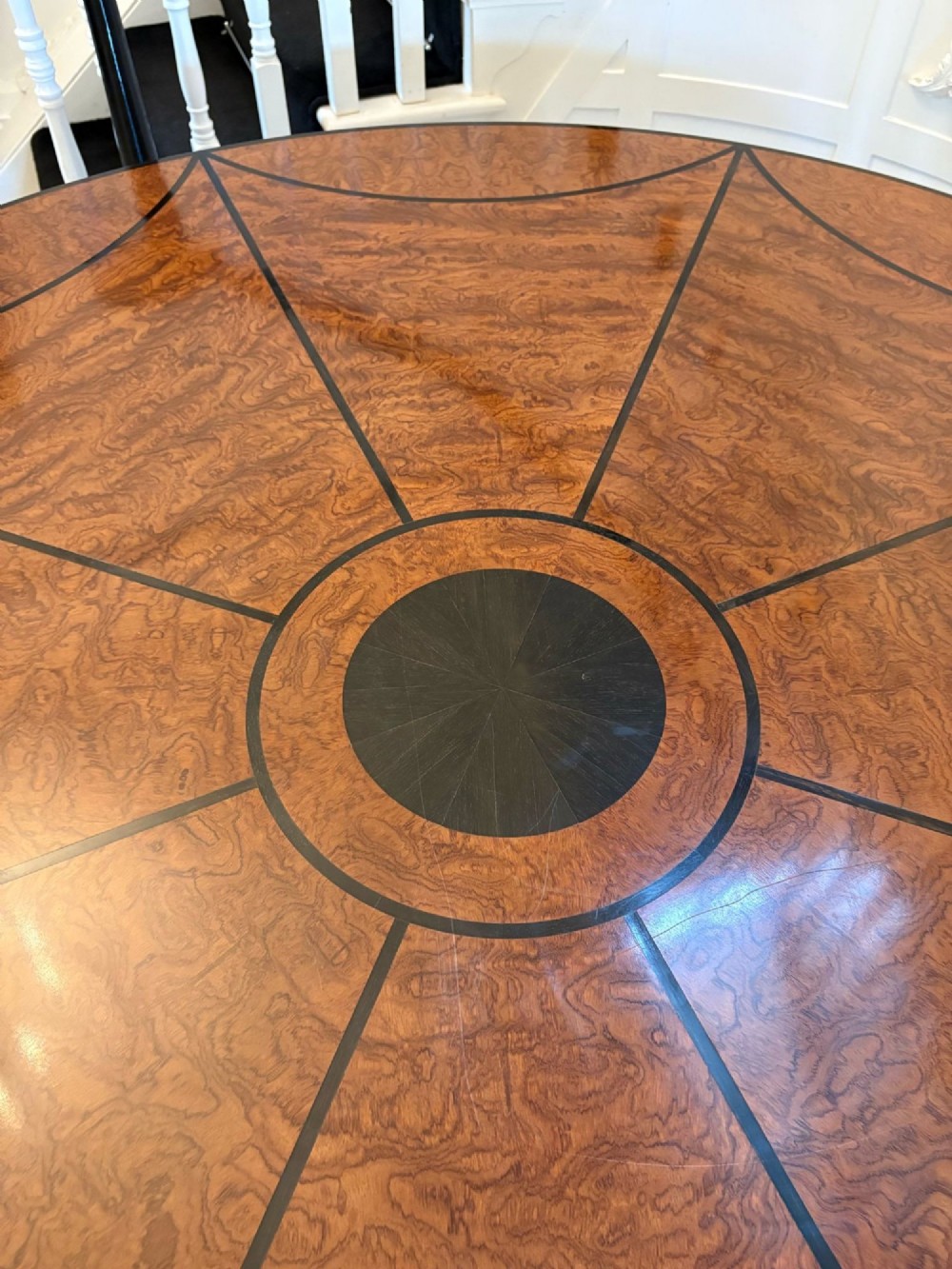 A large circular dining table crafted from burr pollard oak with geometric ebony inlay and ebonised bobbin legs. View VI