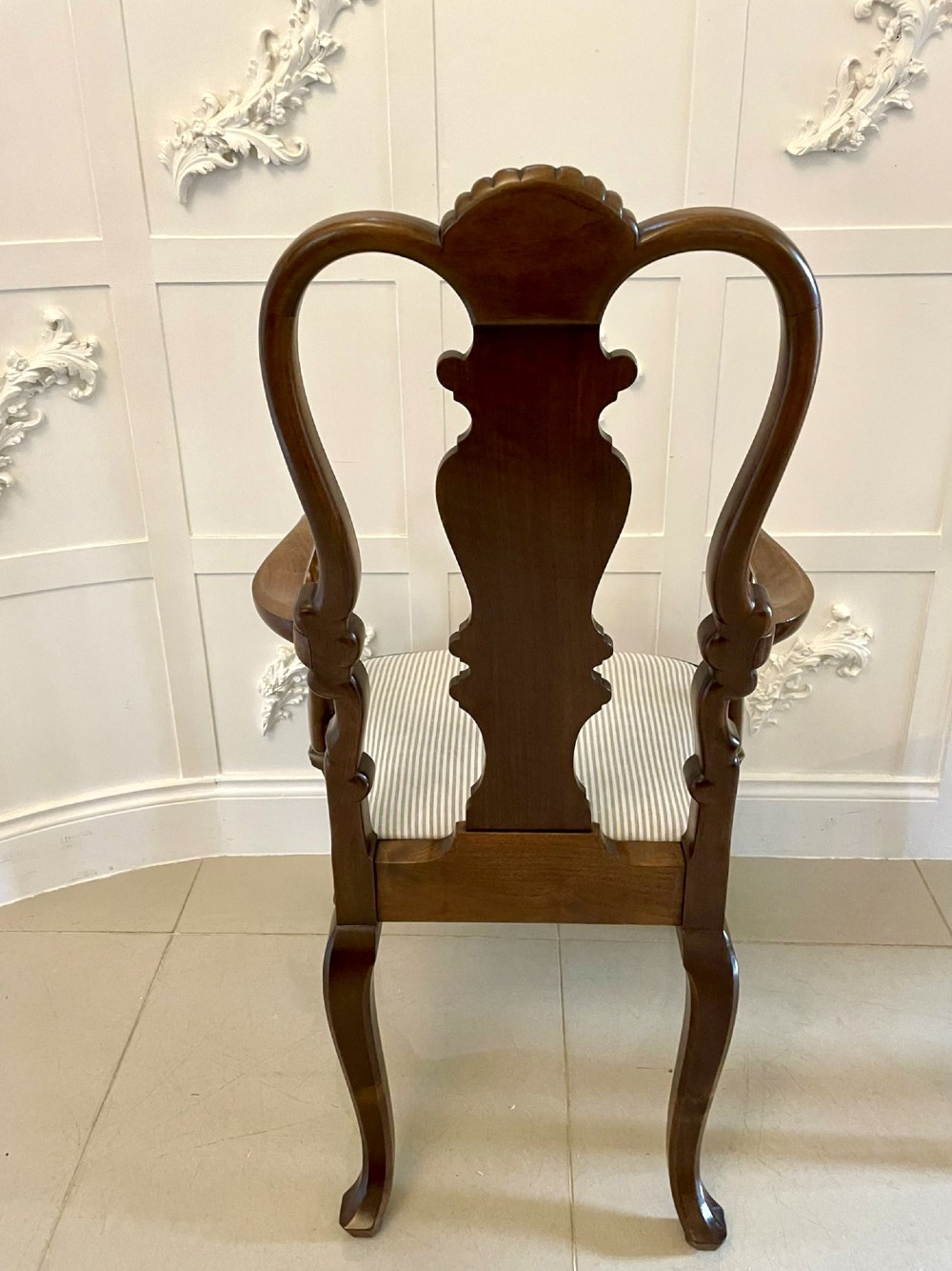 A set of ten walnut dining chairs featuring carved shell crests, splat backs, cabriole legs, and striped upholstered seats. View V