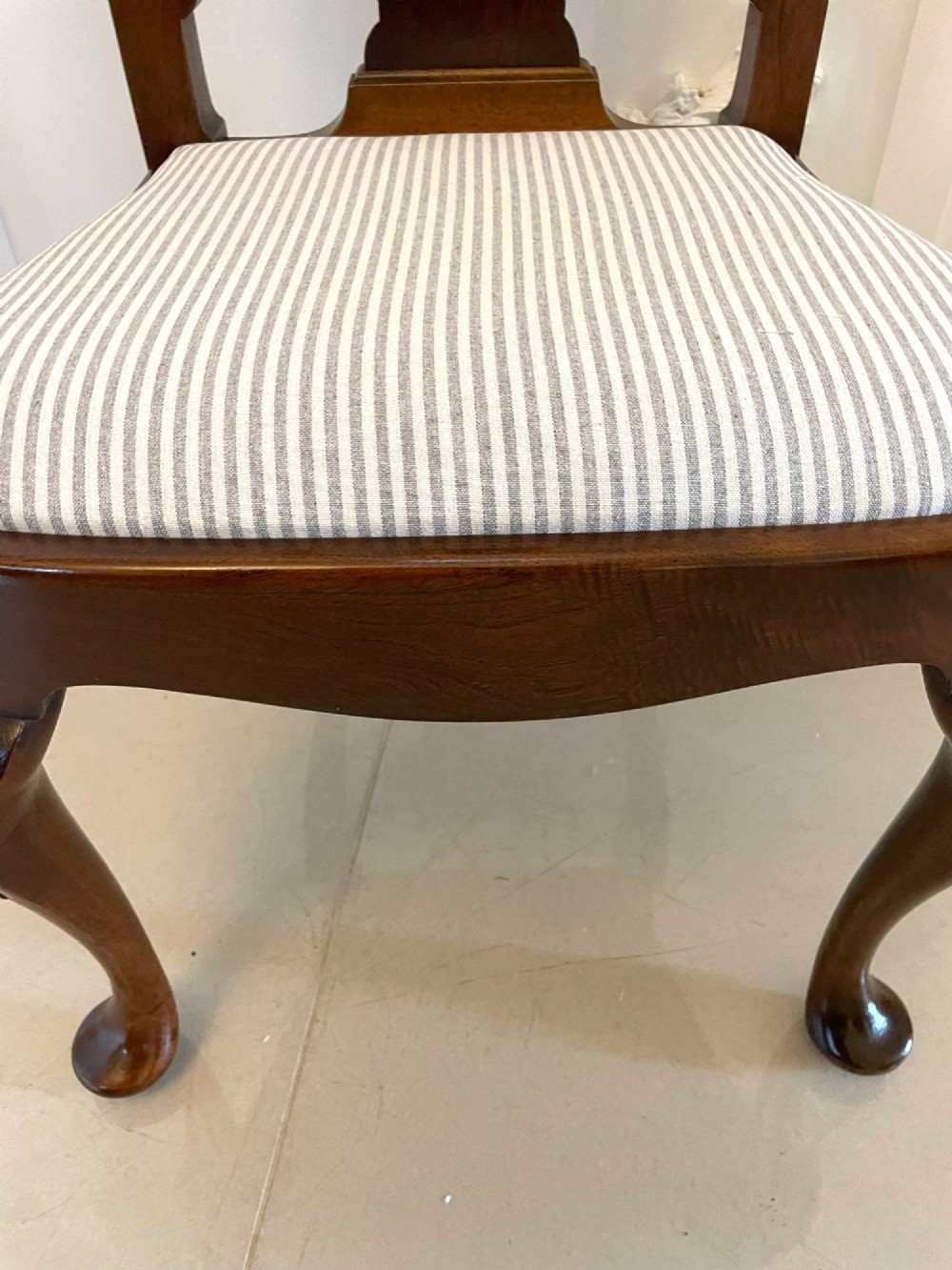 A set of ten walnut dining chairs featuring carved shell crests, splat backs, cabriole legs, and striped upholstered seats. View X