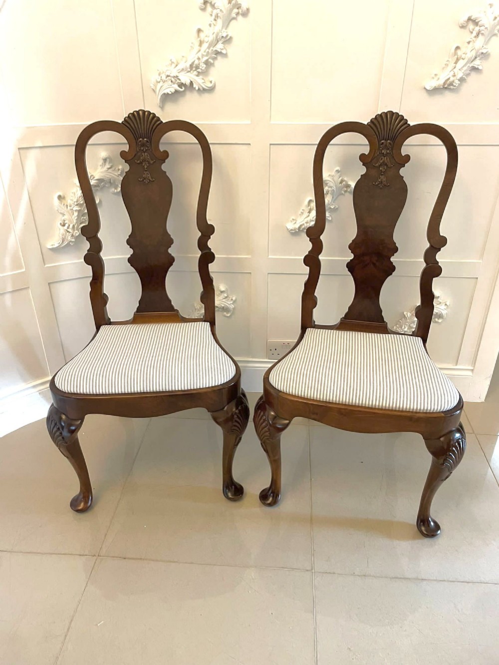A set of ten walnut dining chairs featuring carved shell crests, splat backs, cabriole legs, and striped upholstered seats. View XIV