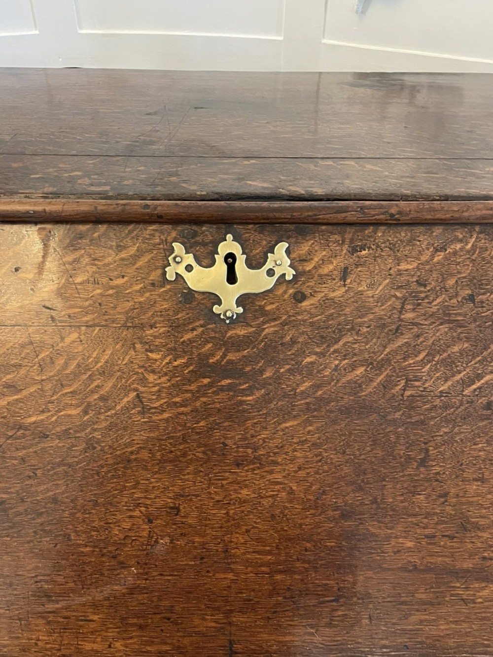 A 17th-century oak writing bureau featuring a slant-front lid above multiple drawers with brass teardrop handles and bracket feet. View II