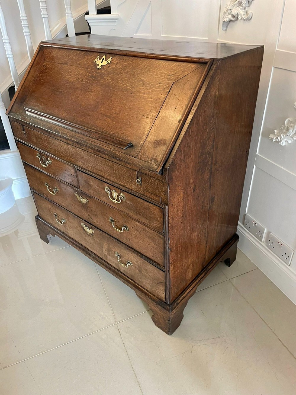 A 17th-century oak writing bureau featuring a slant-front lid above multiple drawers with brass teardrop handles and bracket feet. View VIII