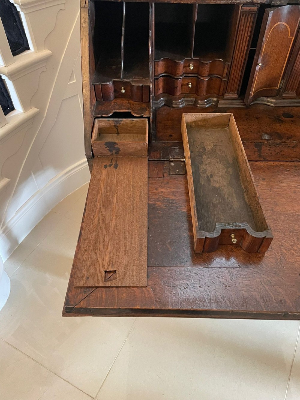 A 17th-century oak writing bureau featuring a slant-front lid above multiple drawers with brass teardrop handles and bracket feet. View XIV
