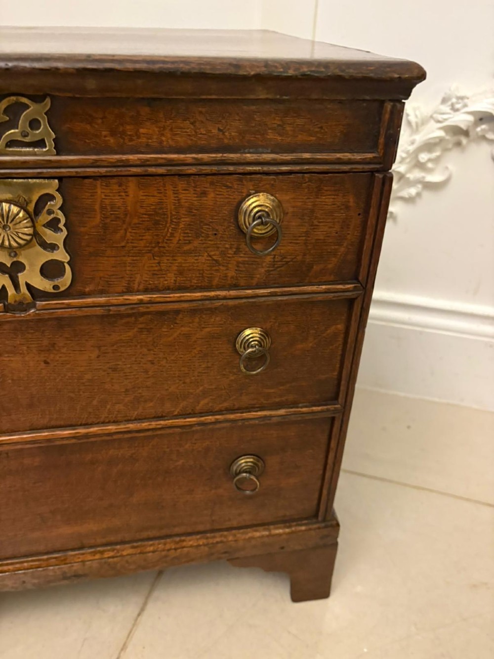 An early 18th-century dark oak box coffer styled as a miniature chest of drawers with decorative brass escutcheons, ring handles, and bracket feet. View IV