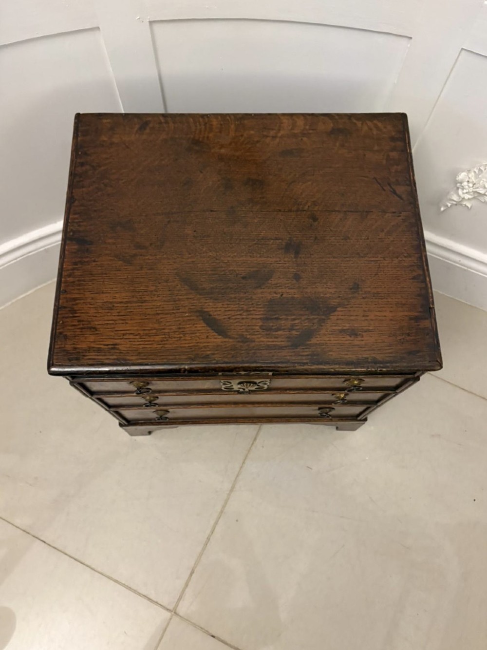 An early 18th-century dark oak box coffer styled as a miniature chest of drawers with decorative brass escutcheons, ring handles, and bracket feet. View VIII