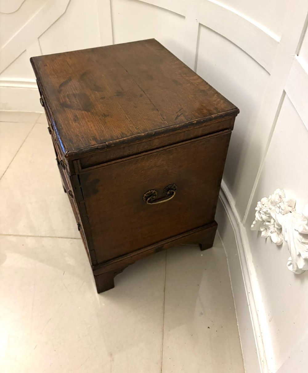 An early 18th-century dark oak box coffer styled as a miniature chest of drawers with decorative brass escutcheons, ring handles, and bracket feet. View IX