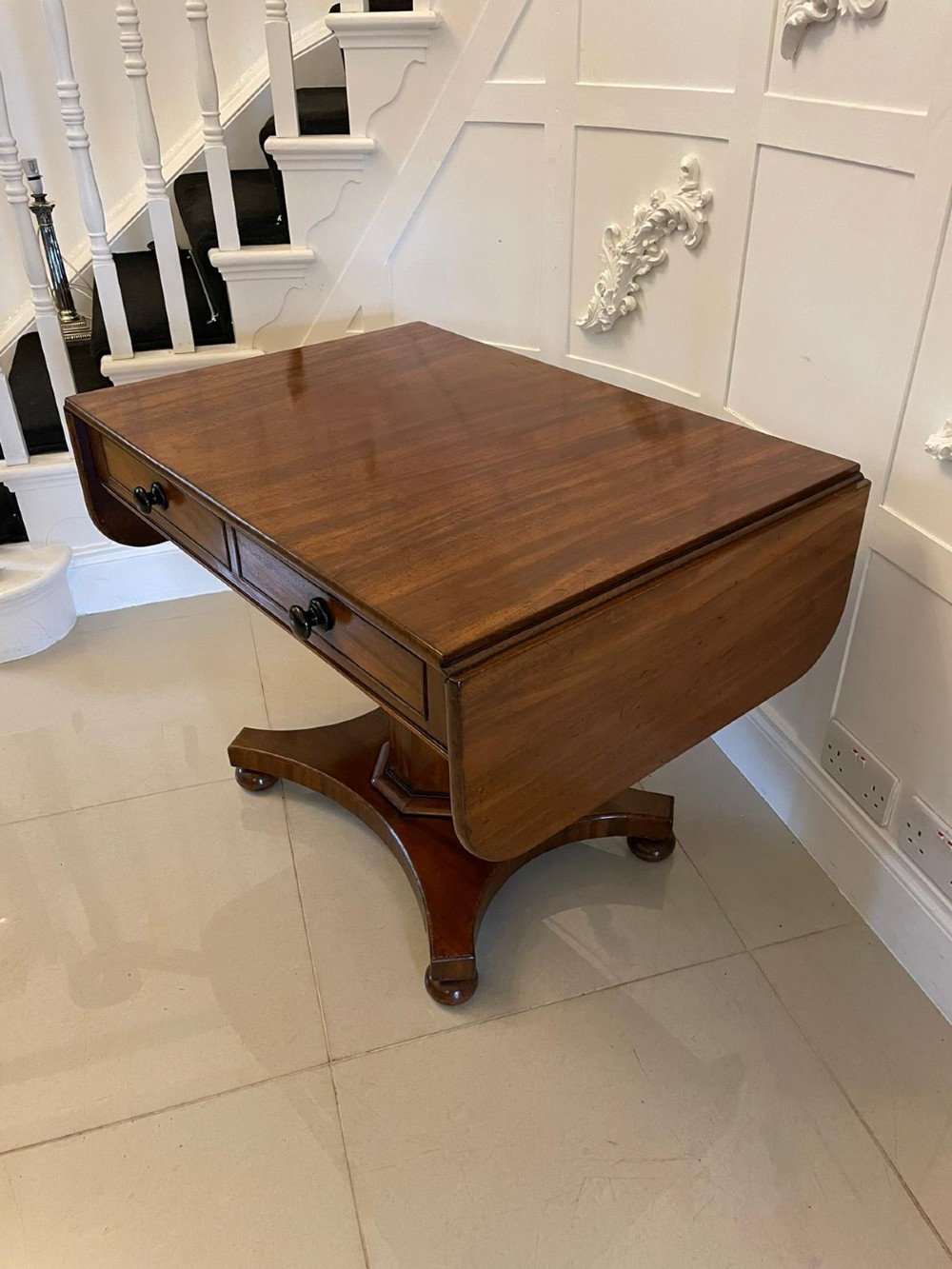 A Regency mahogany sofa table featuring two short drawers with black turned knobs, twin drop-leaf flaps, a central octagonal pedestal, and a quadruped base. View V