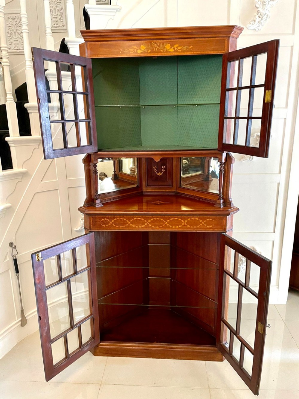 An Edwardian mahogany corner display cabinet featuring floral satinwood inlay, glazed doors with astragal bars, and a mirrored central niche. View II