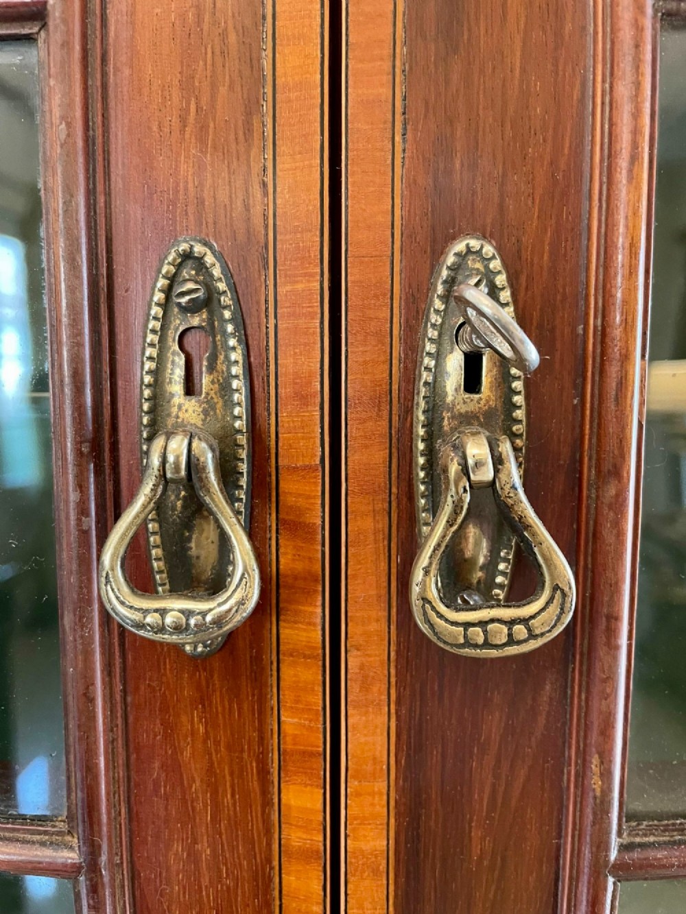 An Edwardian mahogany corner display cabinet featuring floral satinwood inlay, glazed doors with astragal bars, and a mirrored central niche. View V