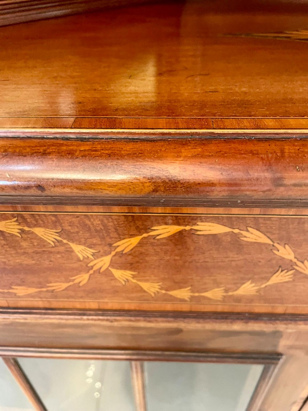 An Edwardian mahogany corner display cabinet featuring floral satinwood inlay, glazed doors with astragal bars, and a mirrored central niche. View VI