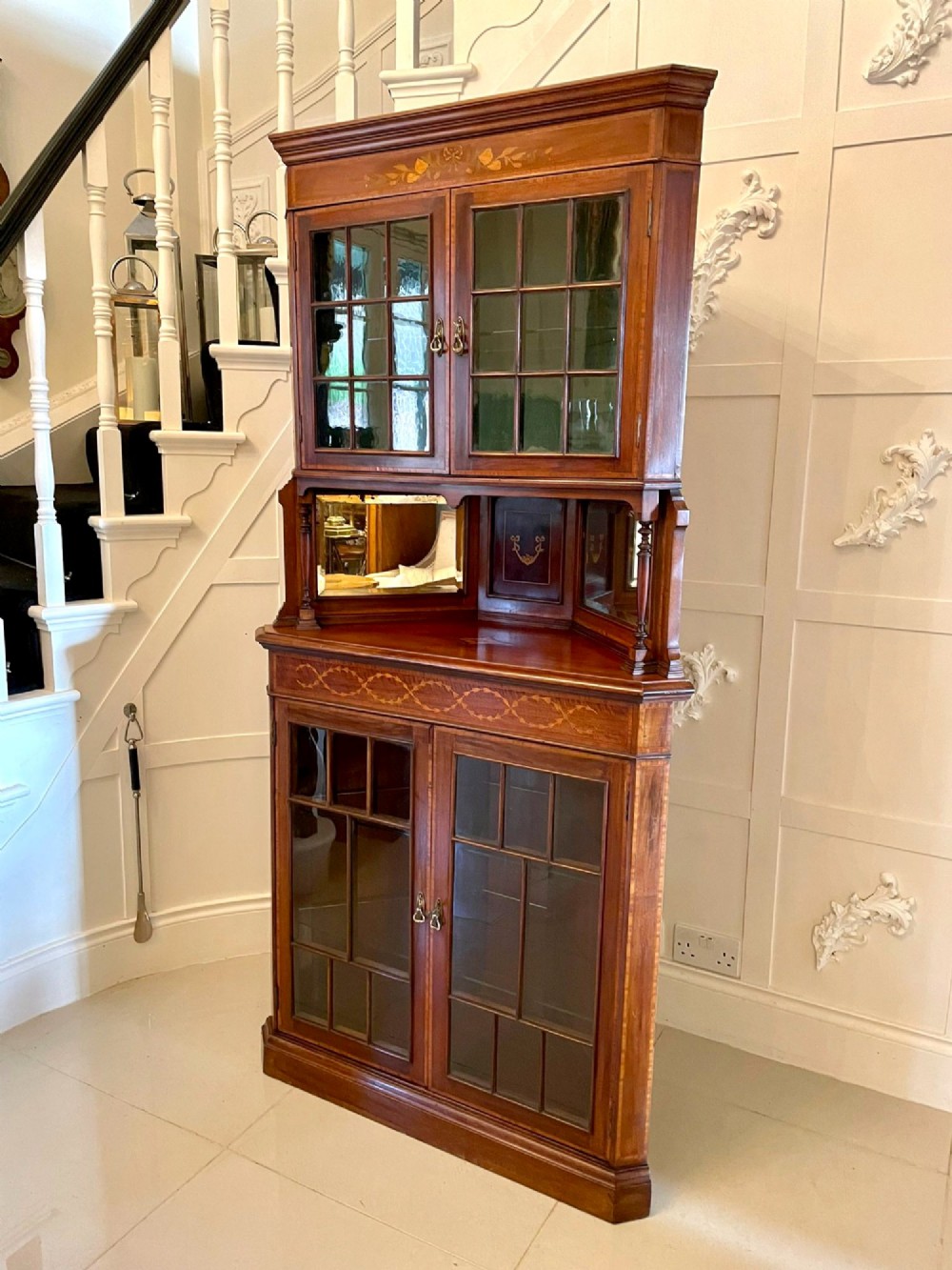 An Edwardian mahogany corner display cabinet featuring floral satinwood inlay, glazed doors with astragal bars, and a mirrored central niche. View VIII