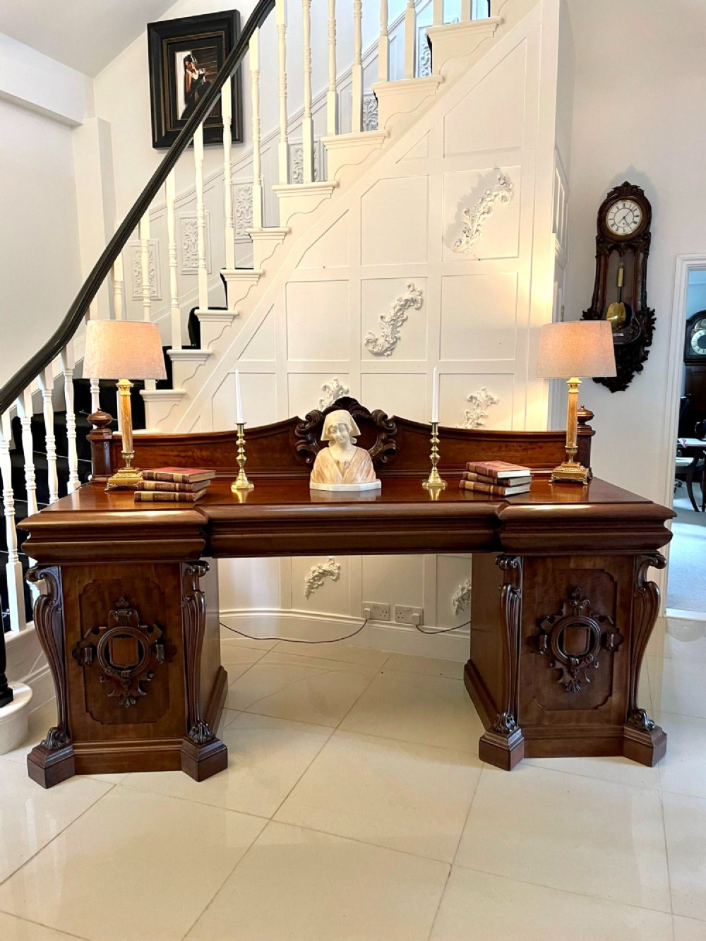 A large William IV mahogany sideboard featuring an ornate carved splashback upstand and two pedestal cupboards with carved scrollwork. View IV