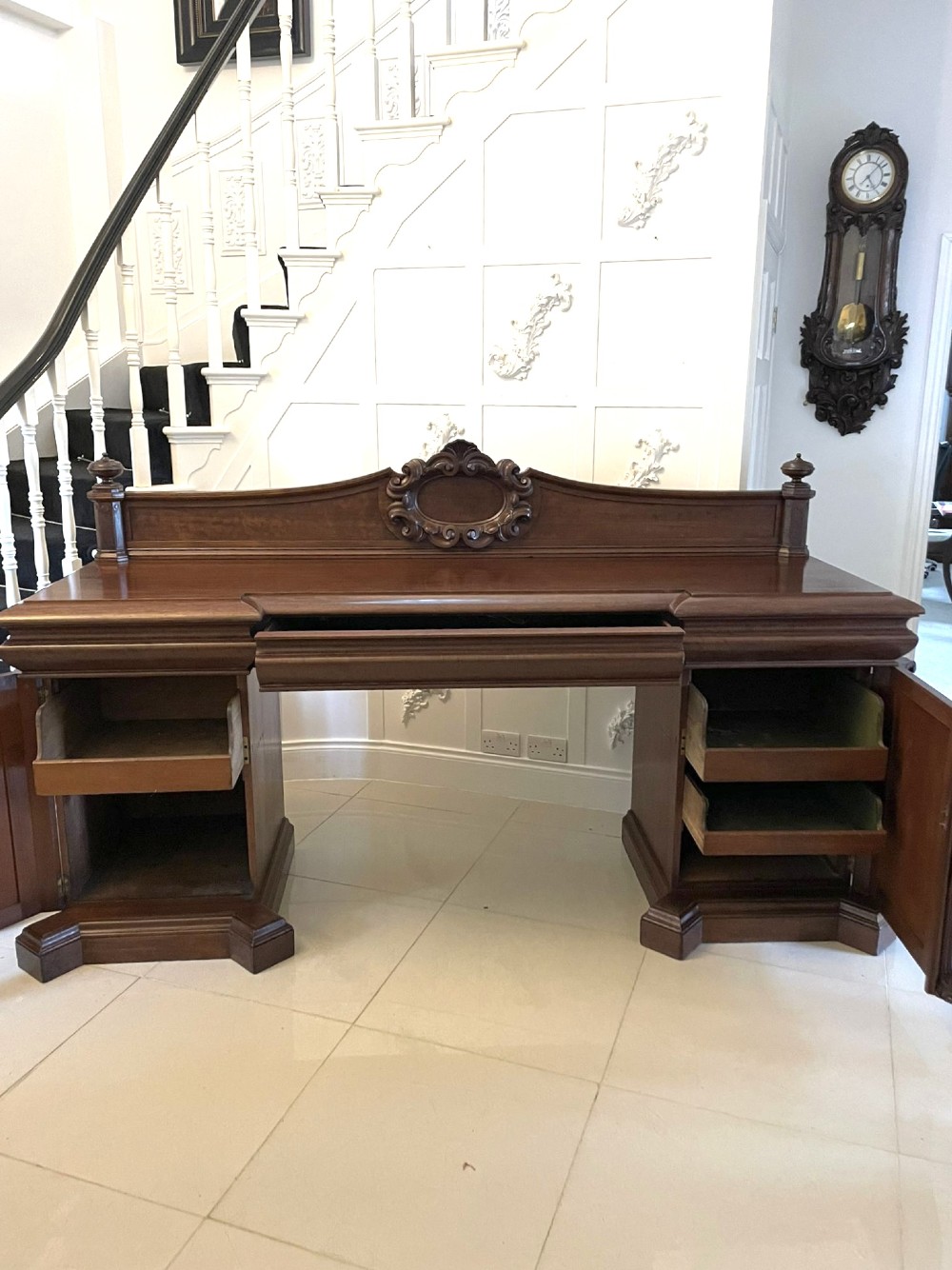 A large William IV mahogany sideboard featuring an ornate carved splashback upstand and two pedestal cupboards with carved scrollwork. View V